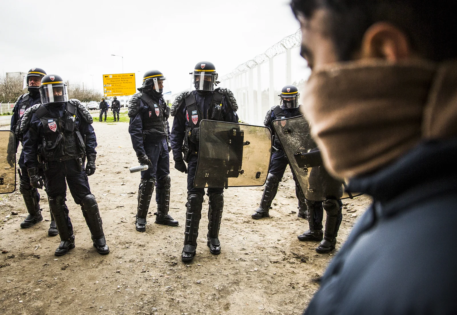 Police guard the entrace to the Jungle Camp in Calais during a protest against the death of a young migrant on a motorway.