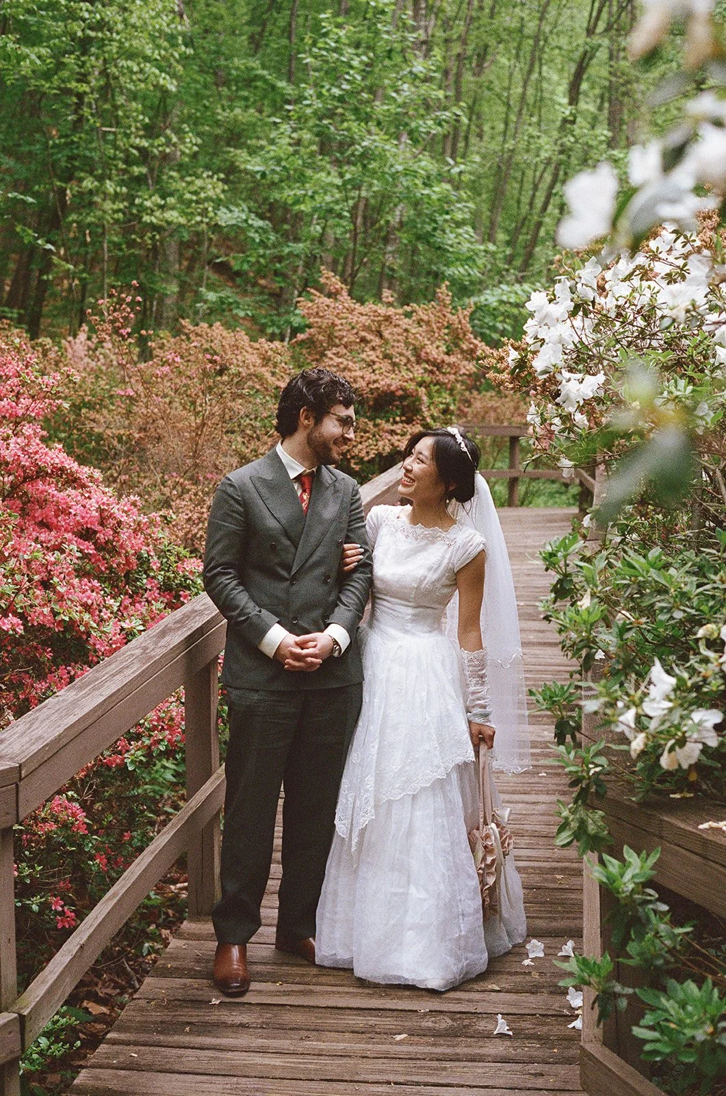 a bride and groom smiling at each other surrounded by azeals