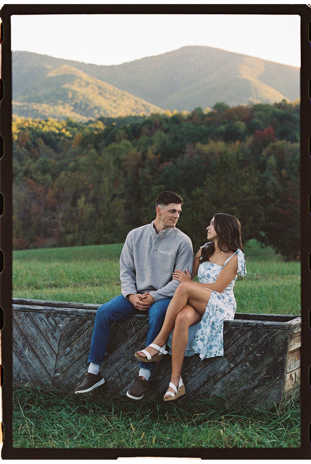 a couple sitting on a wood bench with mountains behind them at green hill park salem va
