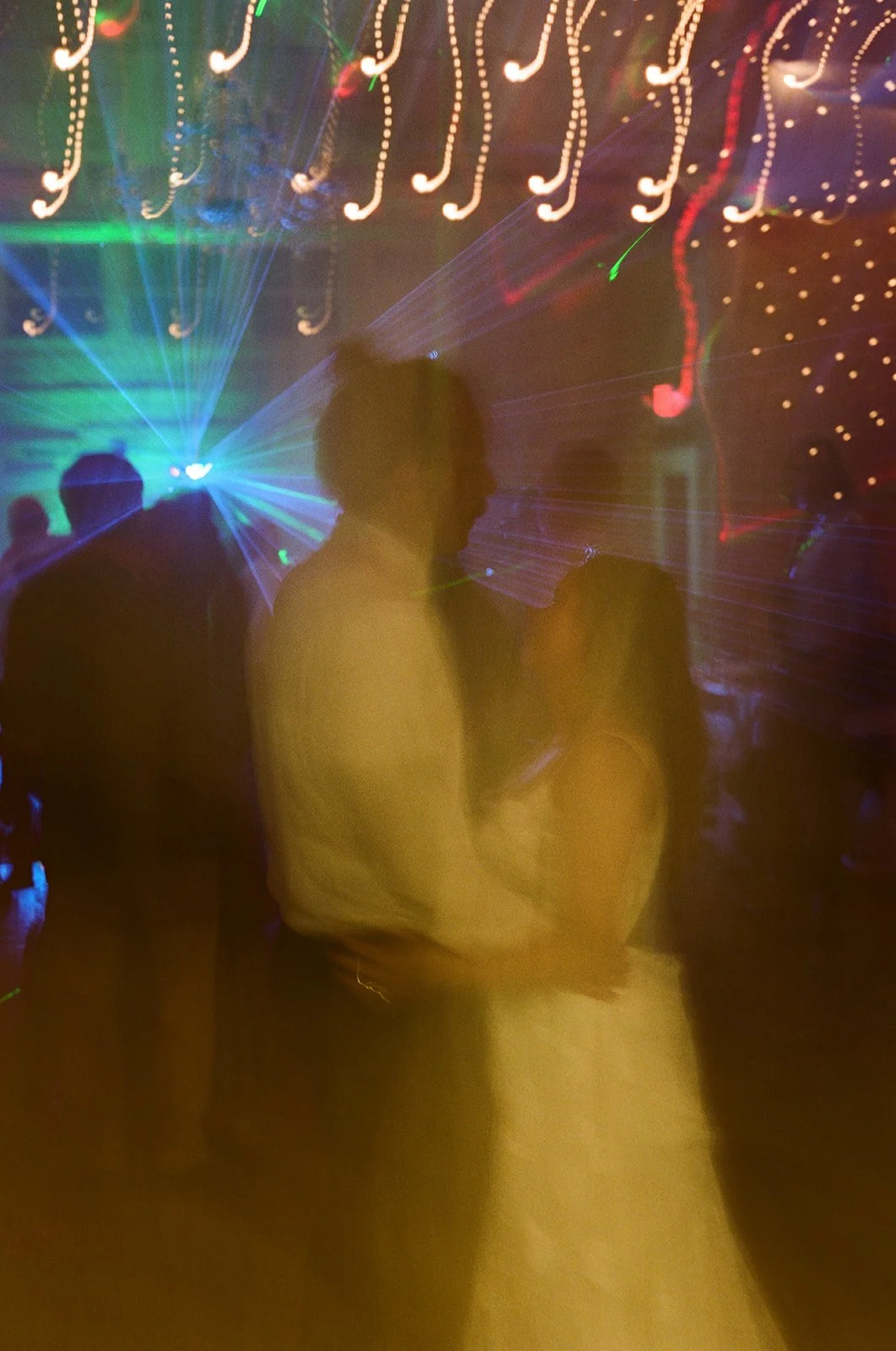 People dancing at a nightclub with colorful laser lights and LED light patterns. ocracoke wedding north carolina Wedding Film Photographer