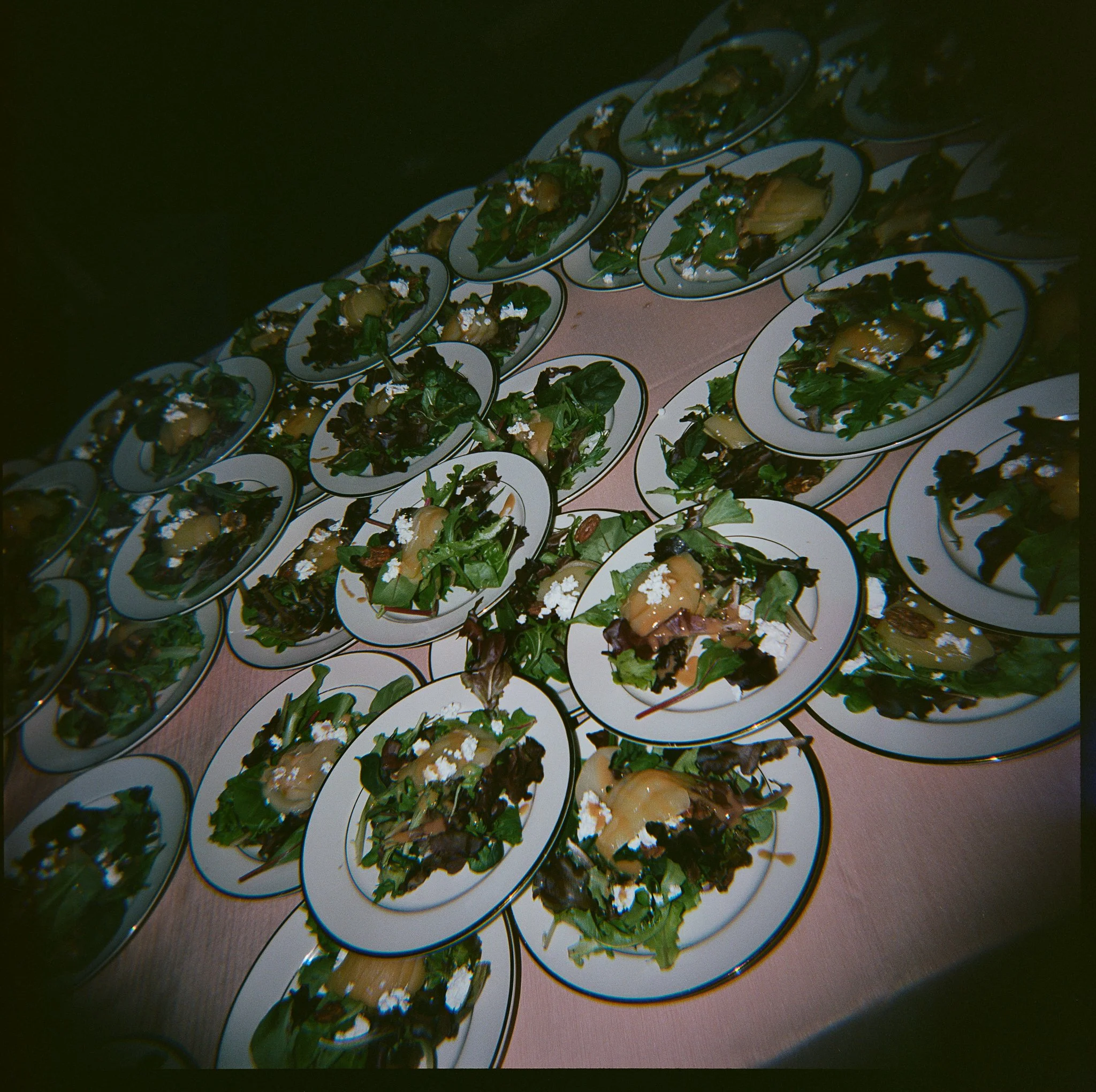 Plates of mixed green salads with pears and cheese on a table. gramercy mansion maryland wedding holga 120 film