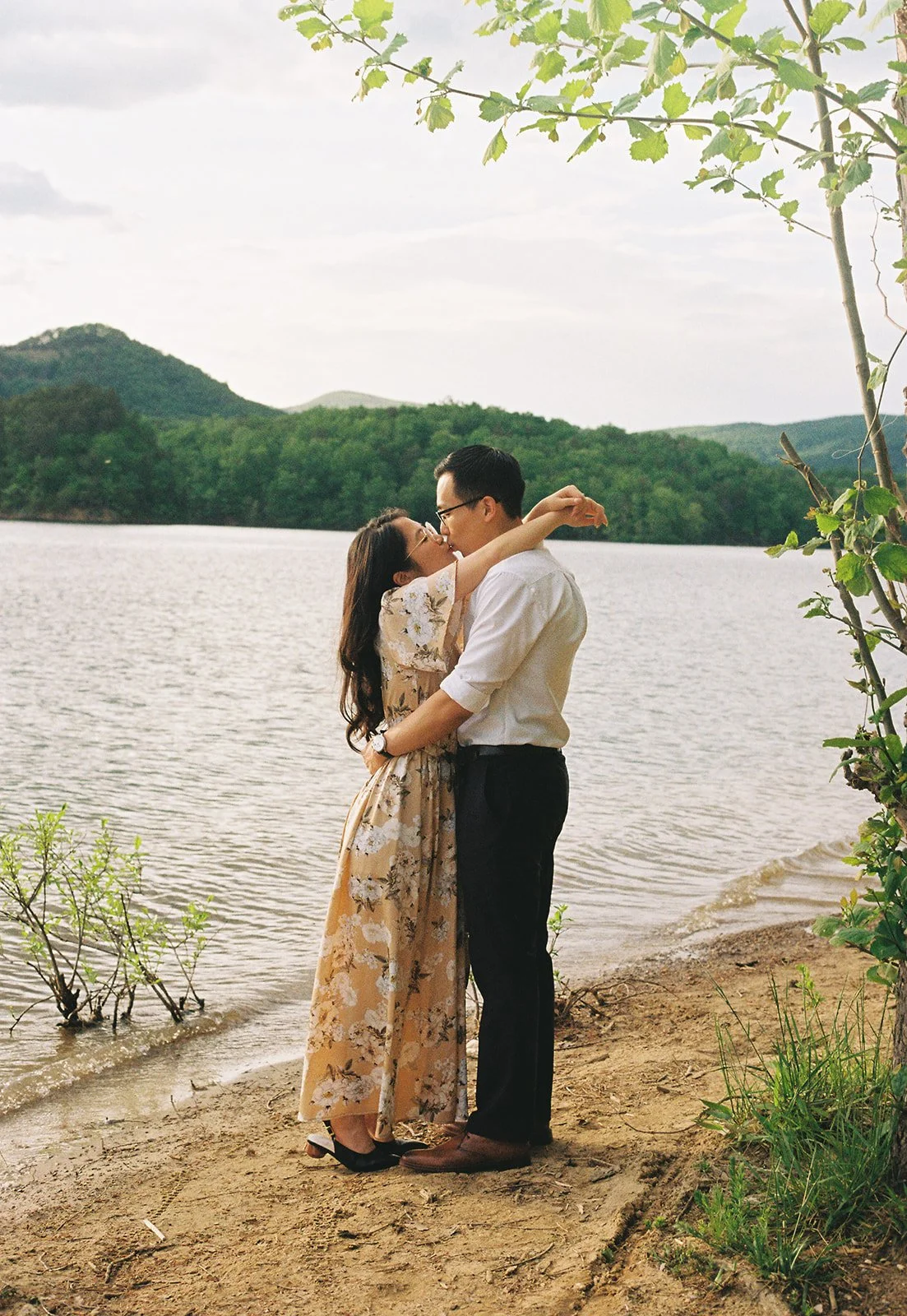 a couple embracing eachother on a sandy embankment at carvins cove reservoir