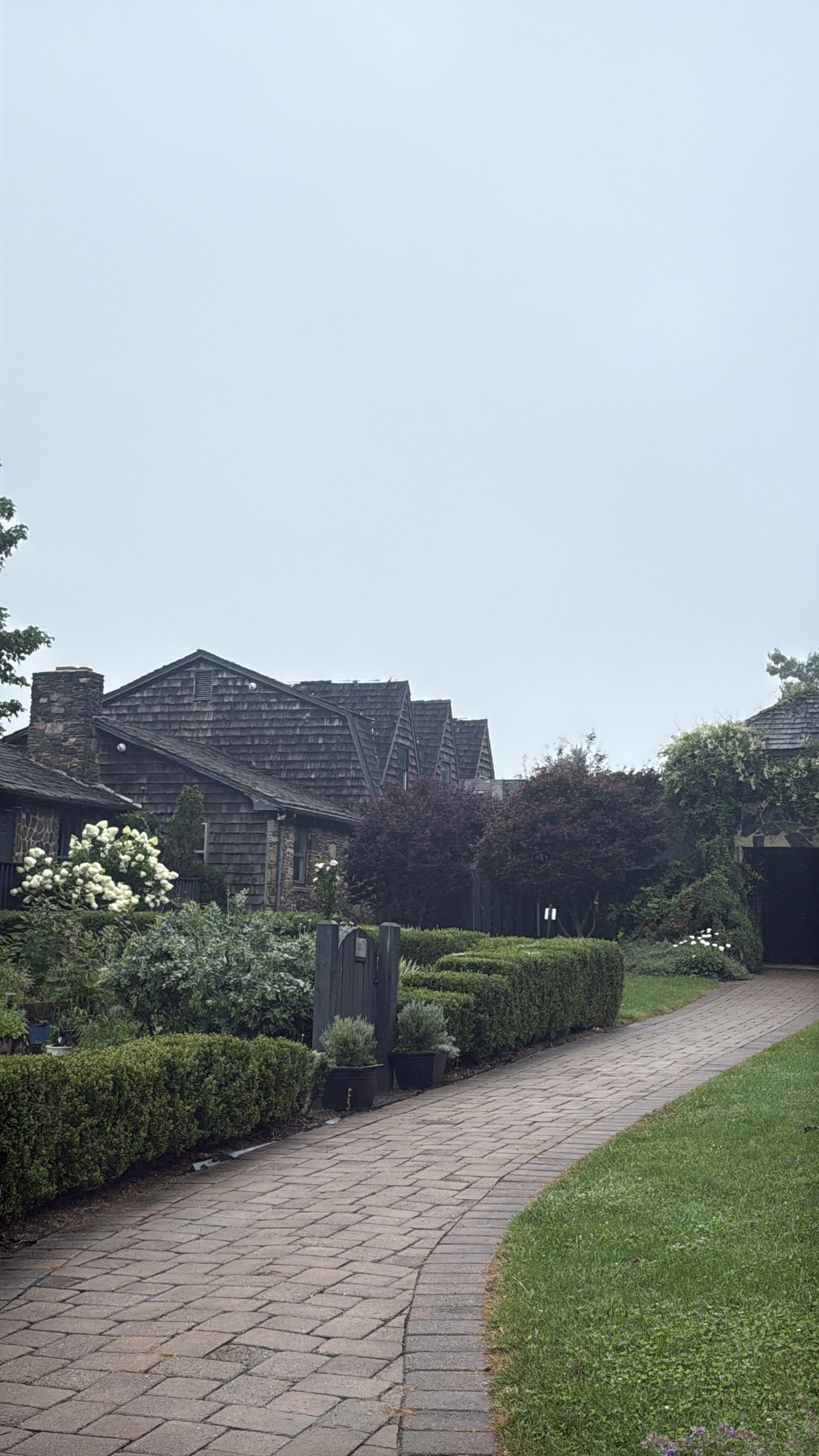 brown wooden building with stone walkway and gardens
