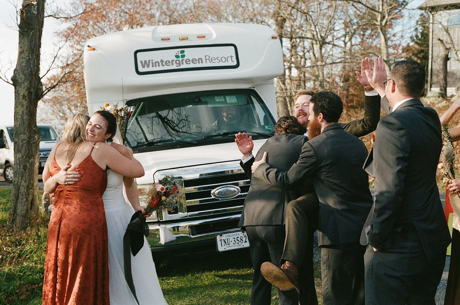 Group of people happily embracing and celebrating at a wedding outdoors near a recreational vehicle. wintergreen resort Wedding Film Photographer