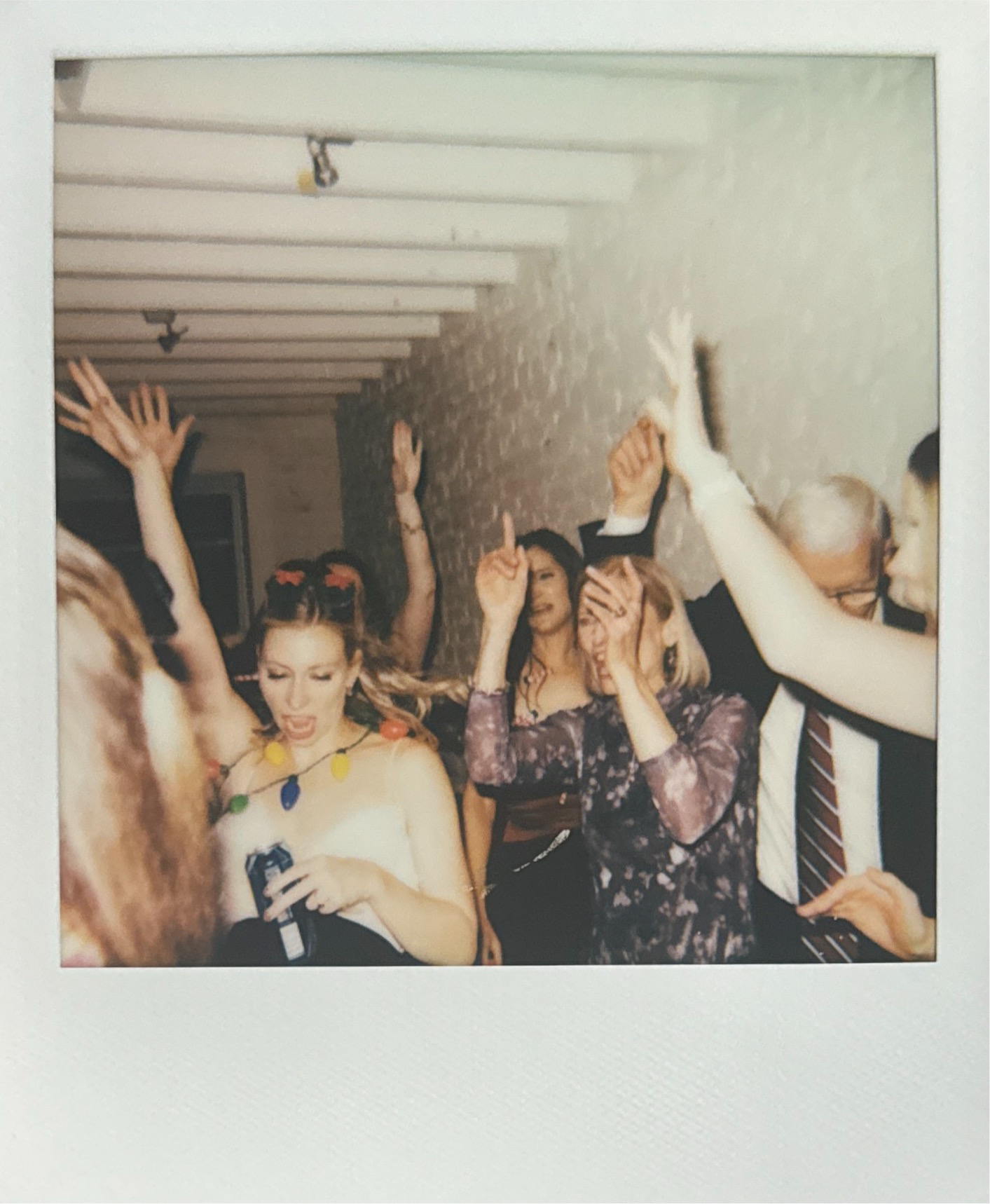 People dancing and having fun at a party, with some singing and raising their hands. Doubles Cafe Wedding Washington DC Film Photographer.
