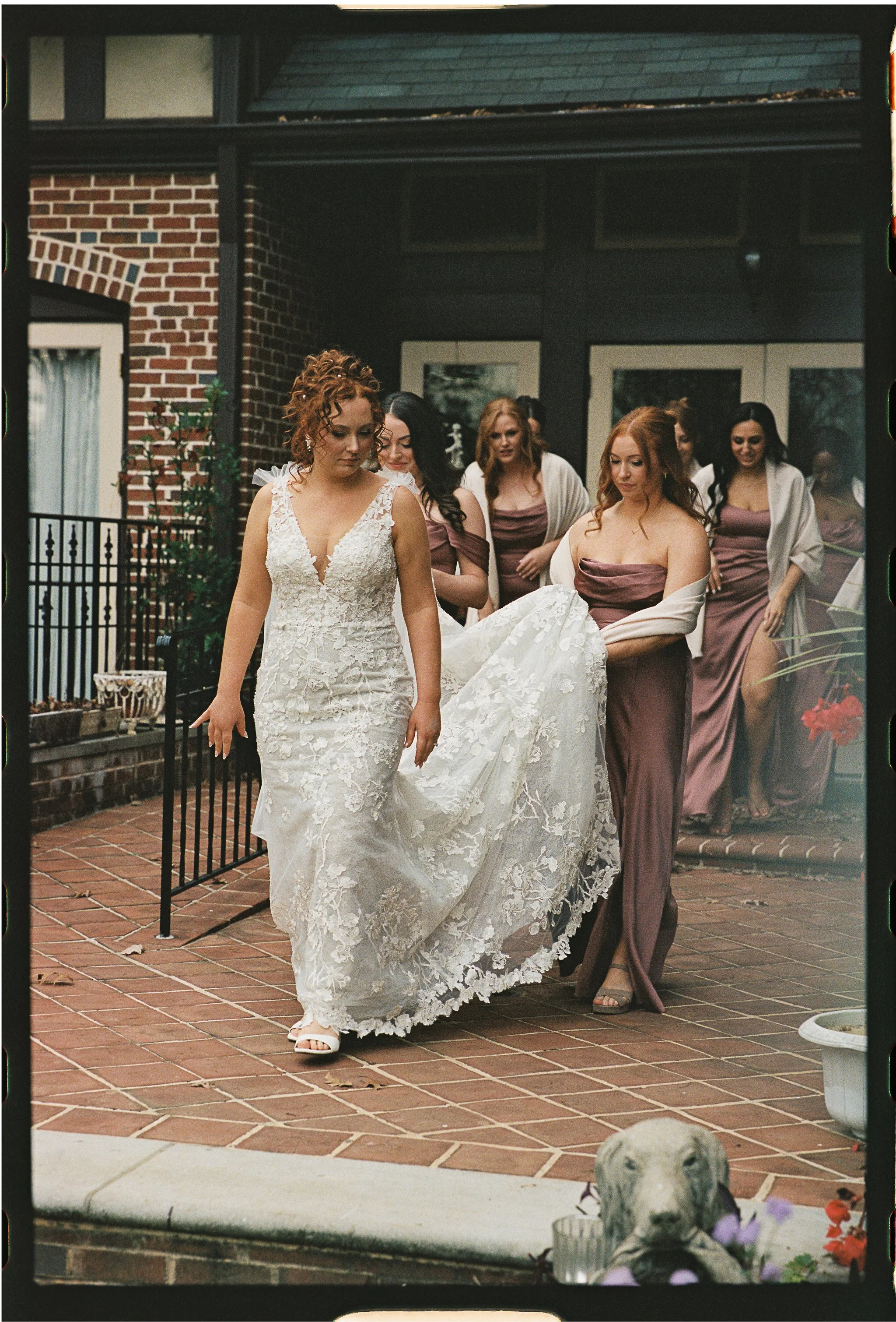 Bride in white lace gown walking with bridesmaids in mauve dresses gramercy mansion maryland wedding