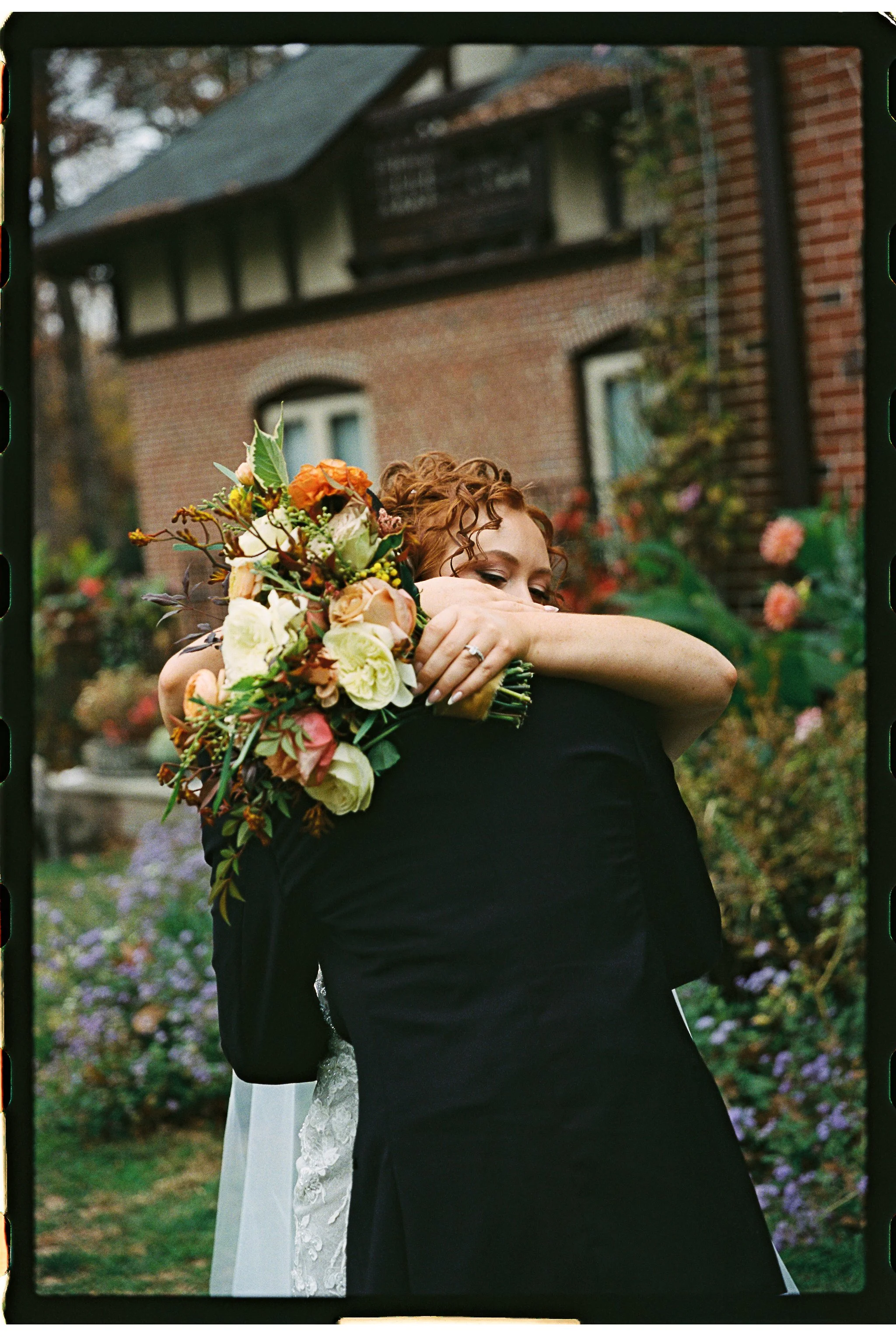 A bride and groom hugging outdoors, the bride holding a bouquet of flowers. gramercy mansion maryland wedding