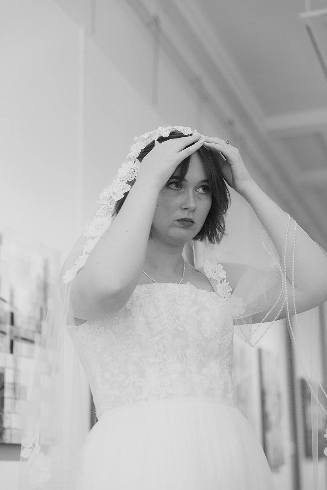 A woman in a wedding dress adjusting her veil in an indoor setting. Staunton Virginia Wedding Photographer.