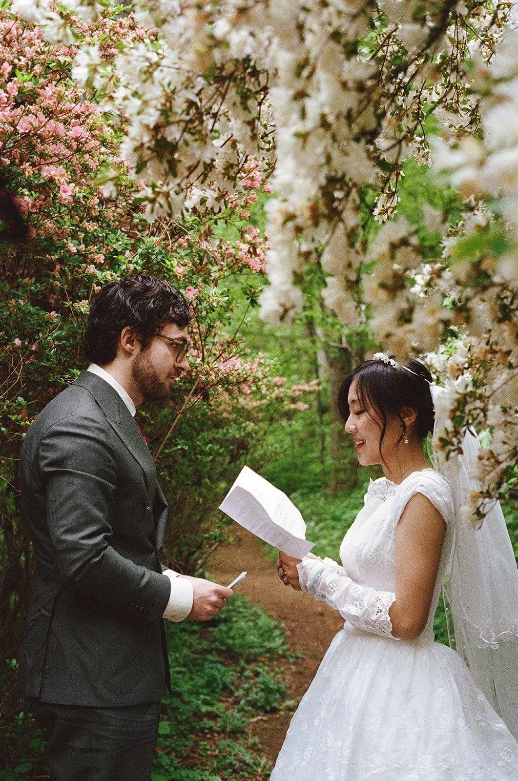 a bride and groom reading vows surrounded by azealas
