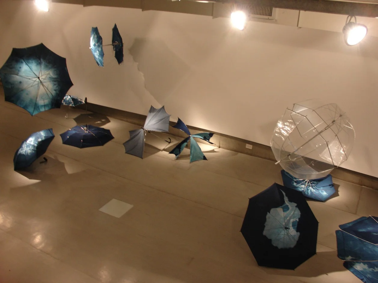 Installation de 36 parapluies modifiés avec le procédé photographique du cyanotype. Galerie Arte X Arte, Buenos Aires, Argentine