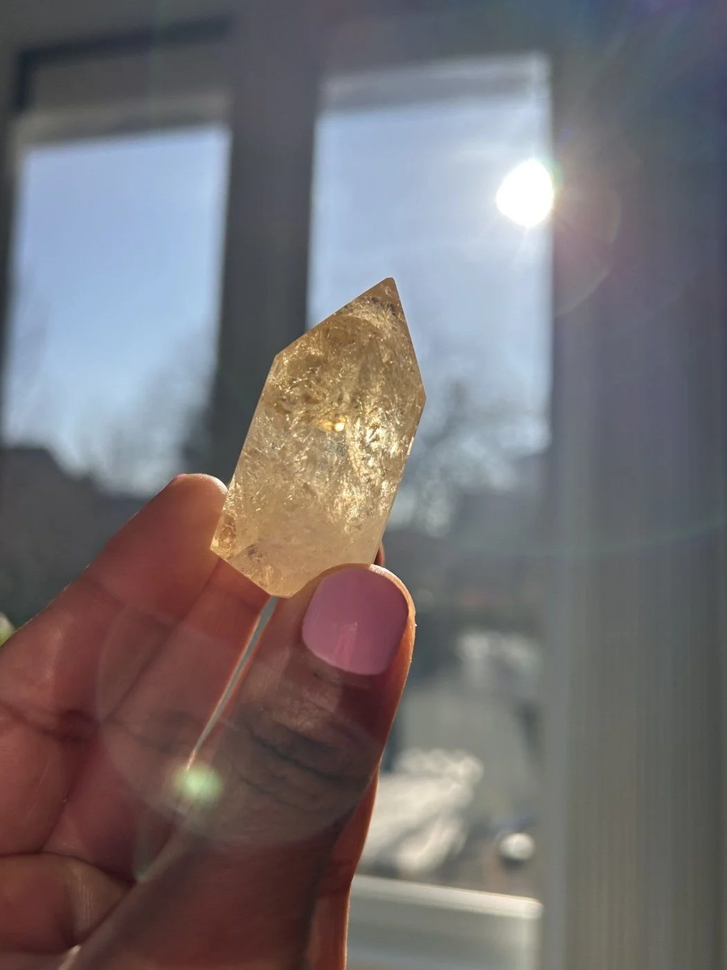 A citrine crystal held up to the morning window light