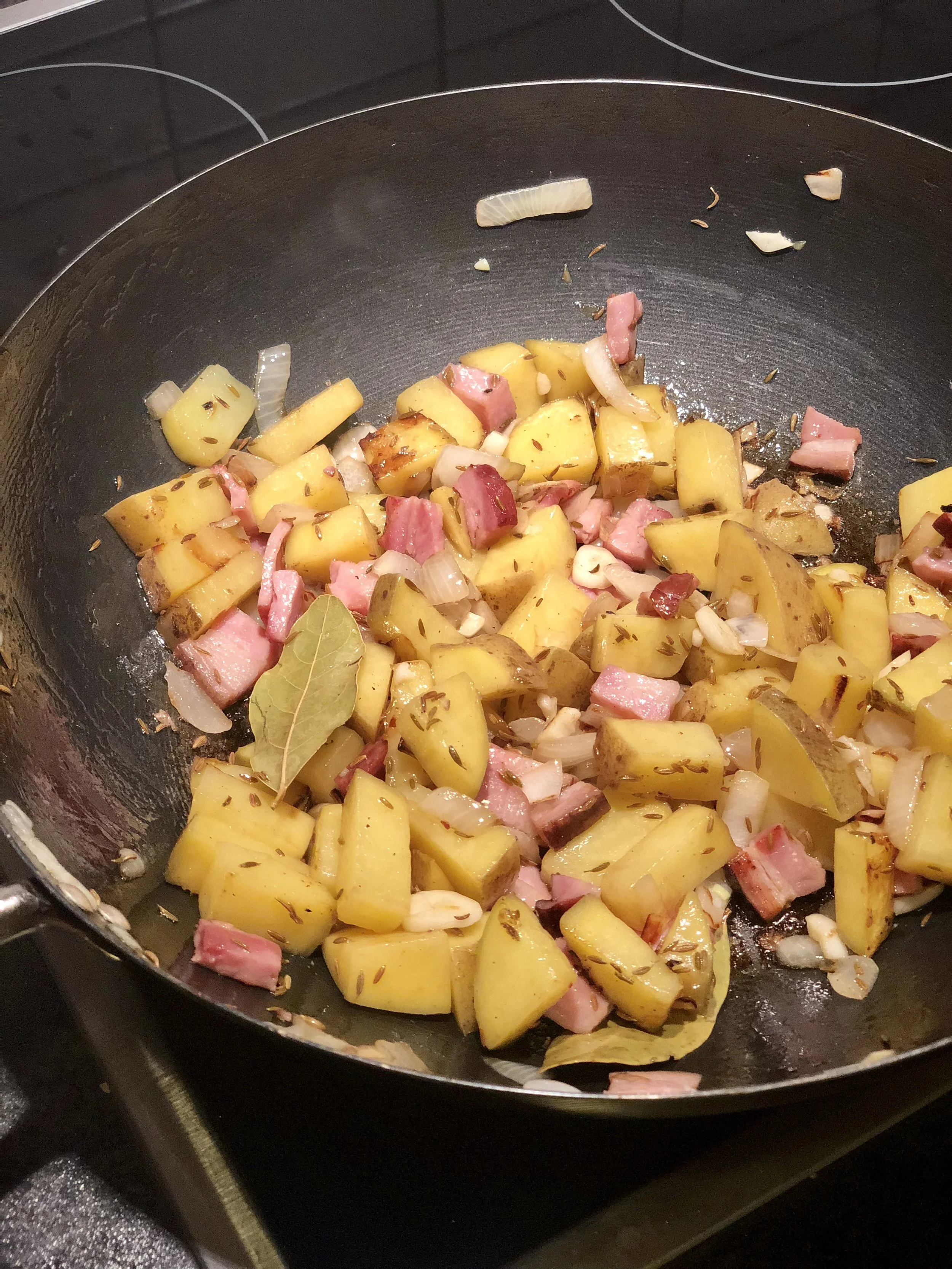 Potatoes cooking with onions, bacon, caraway, and bay leaf.
