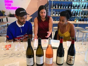 Two people sitting at the DECANTsf bar, with a book of wine maps open and four bottles of wine in front of them.