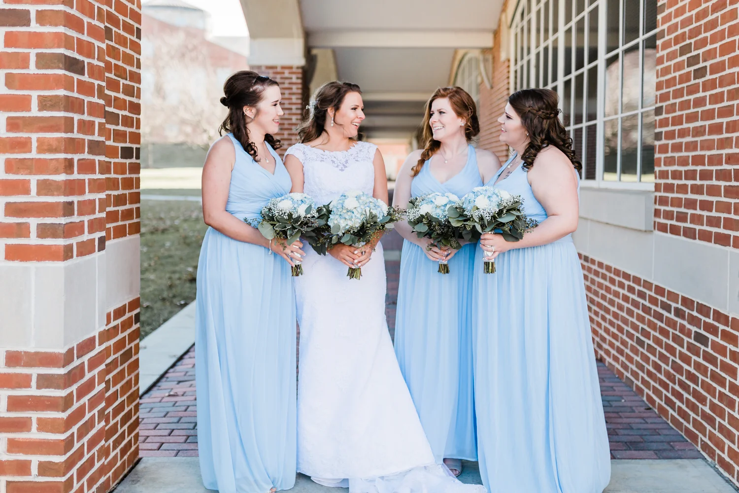 bride and her bridesmaids laughing for portraits with their bouquets