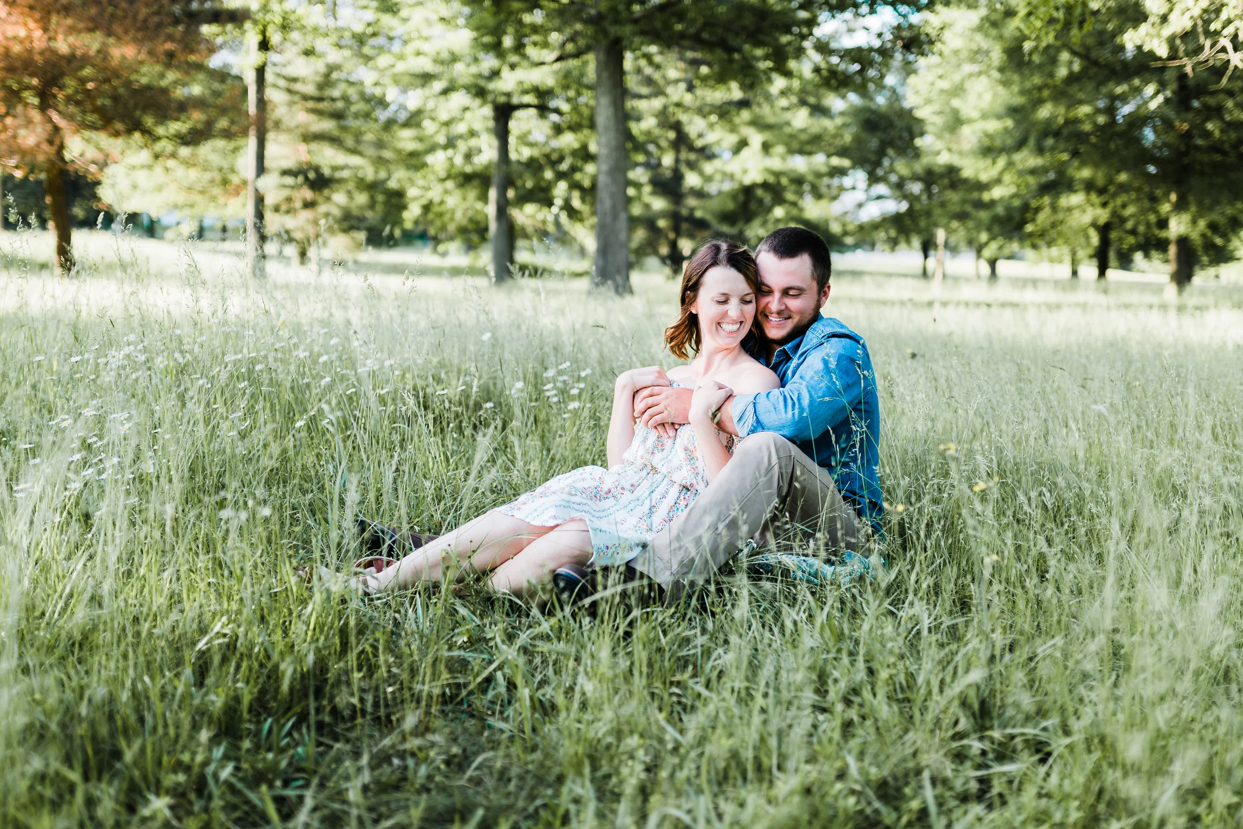 couple snuggling in tall grasses for engagement photos in maryland