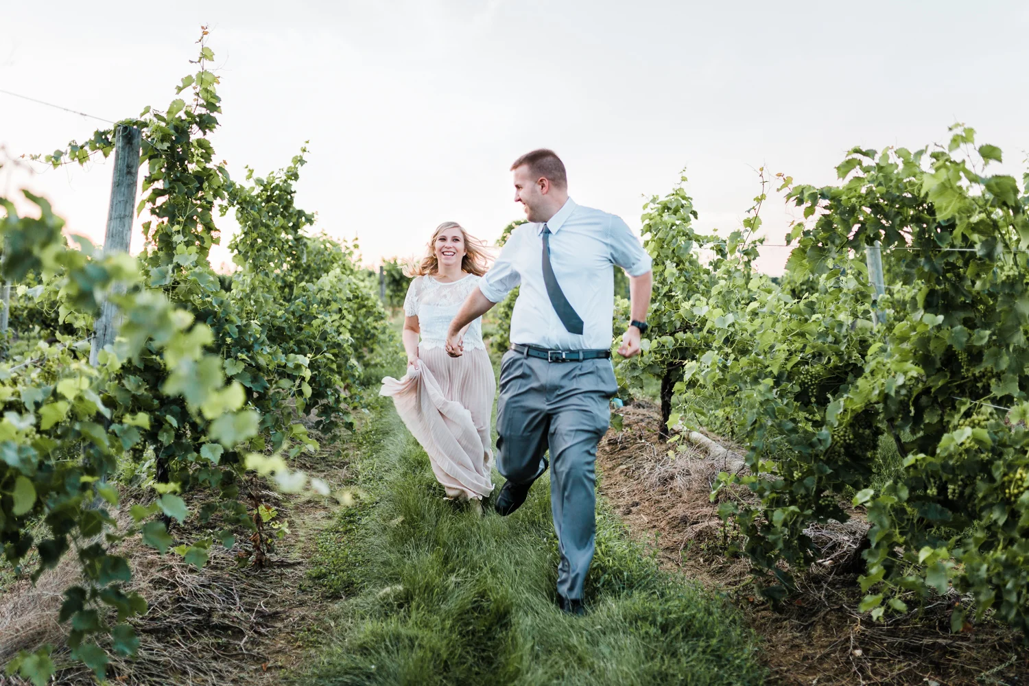 couple romantically running through vineyard during golden hour - top md wedding and engagement photographer