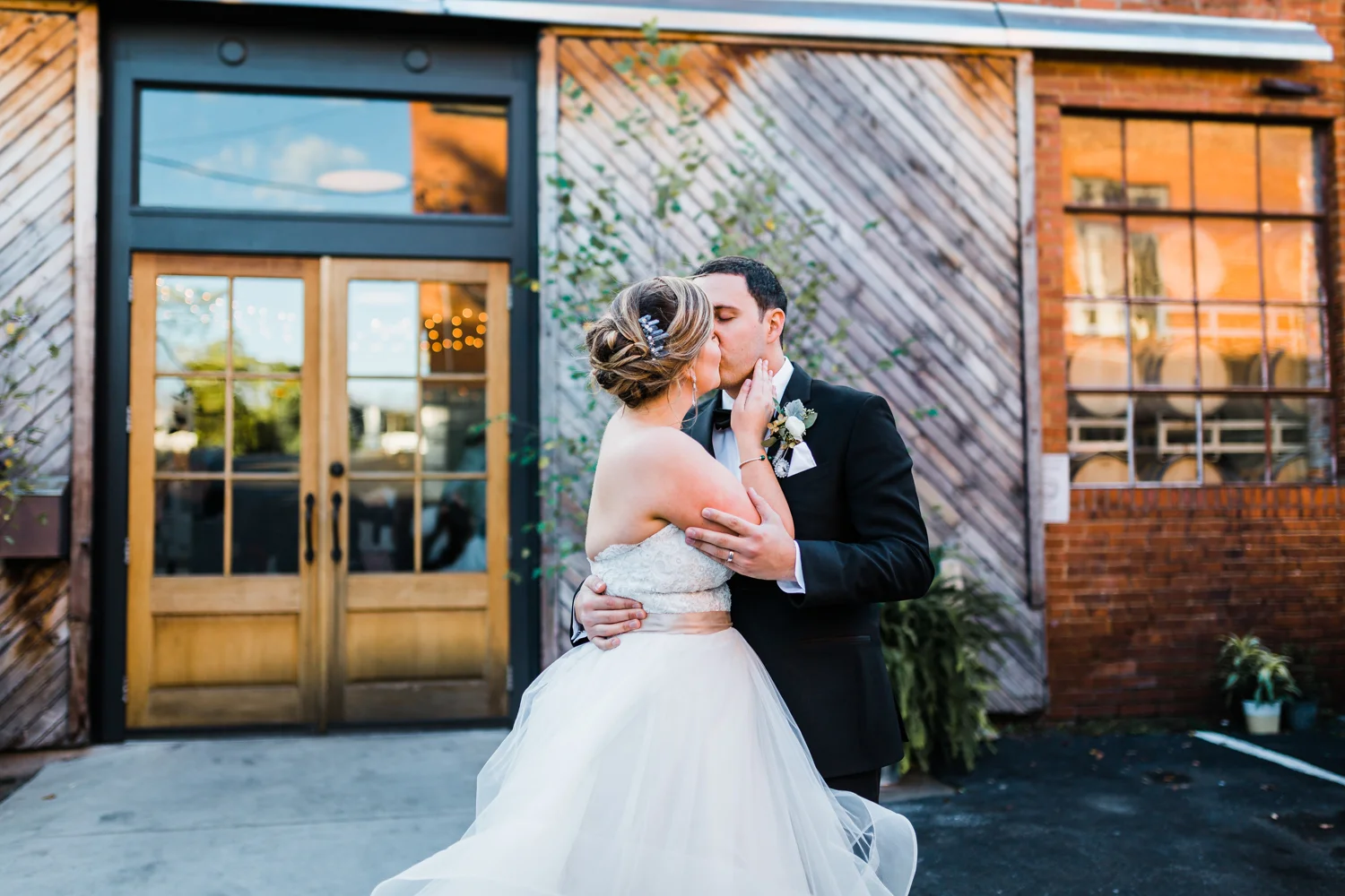 bride and groom kiss outside of McClintock Distilling