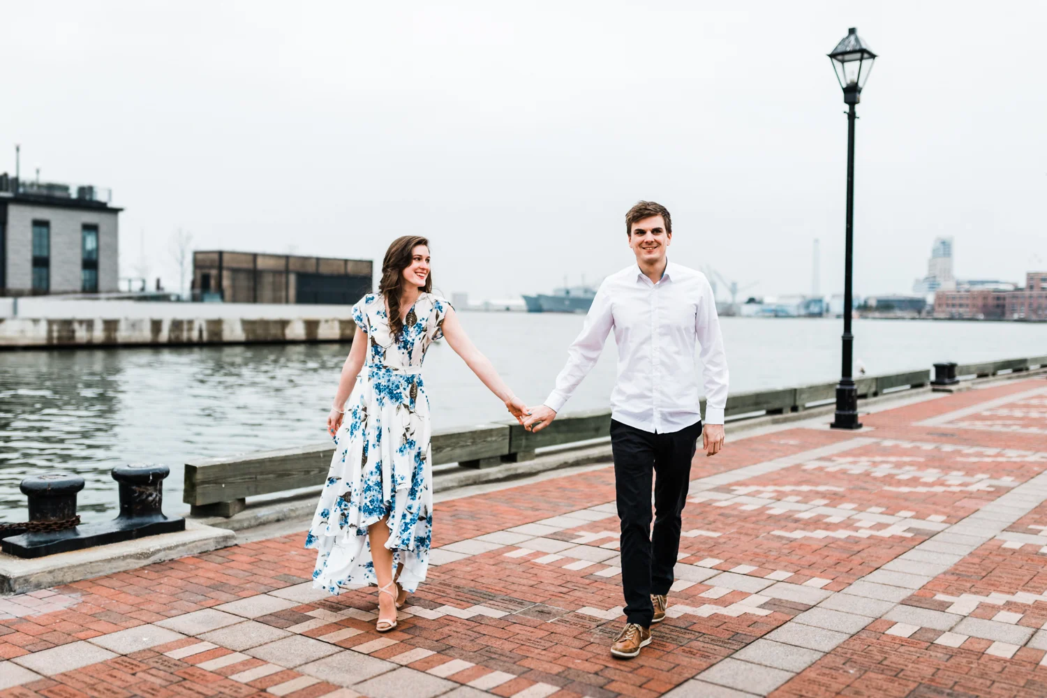 Couple walking and holding hands on promenade at Fells Point - Baltimore, Maryland engagement and wedding photographer