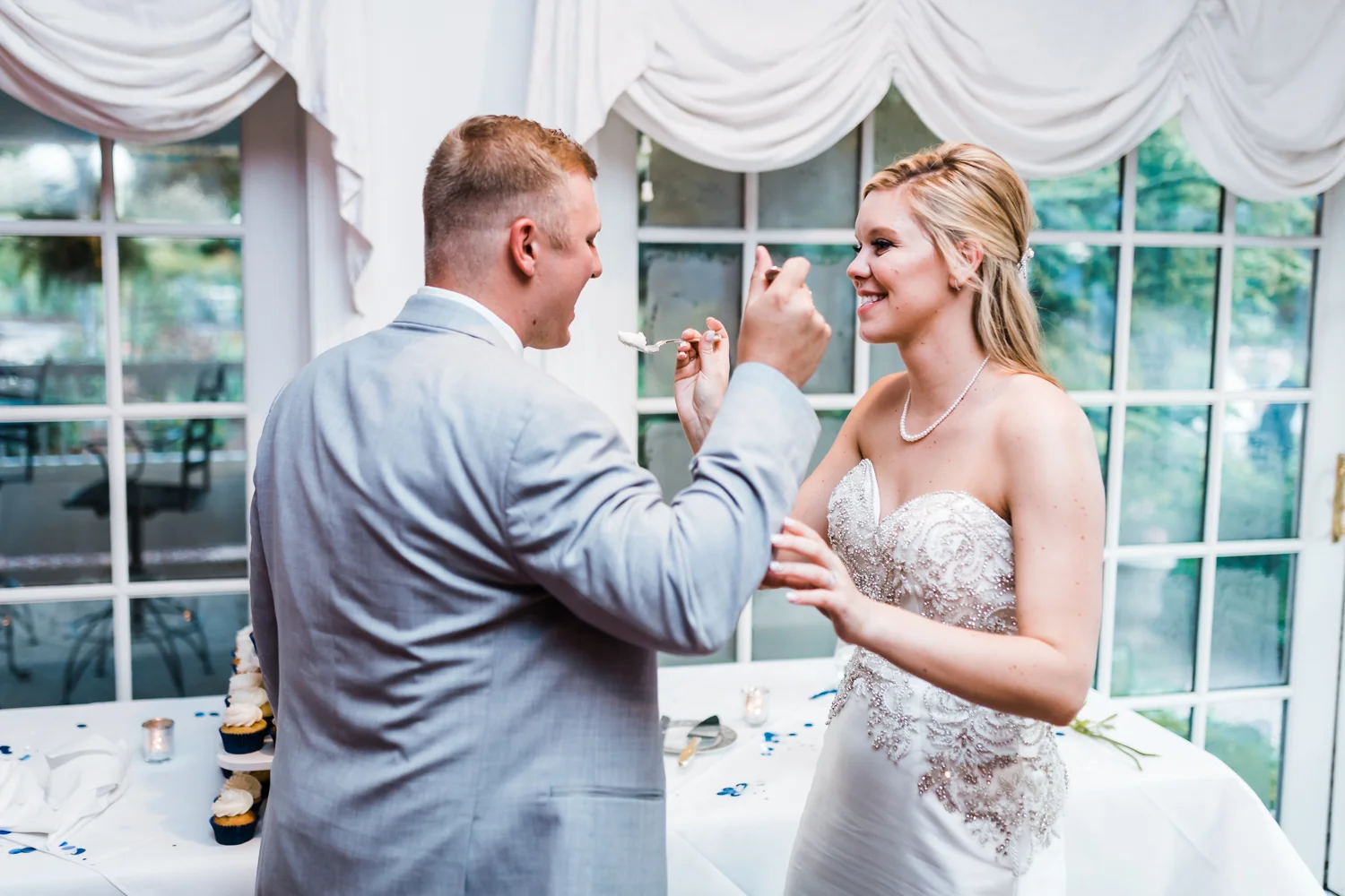 bride and groom feeding each other their wedding cake - maryland wedding photo and video team