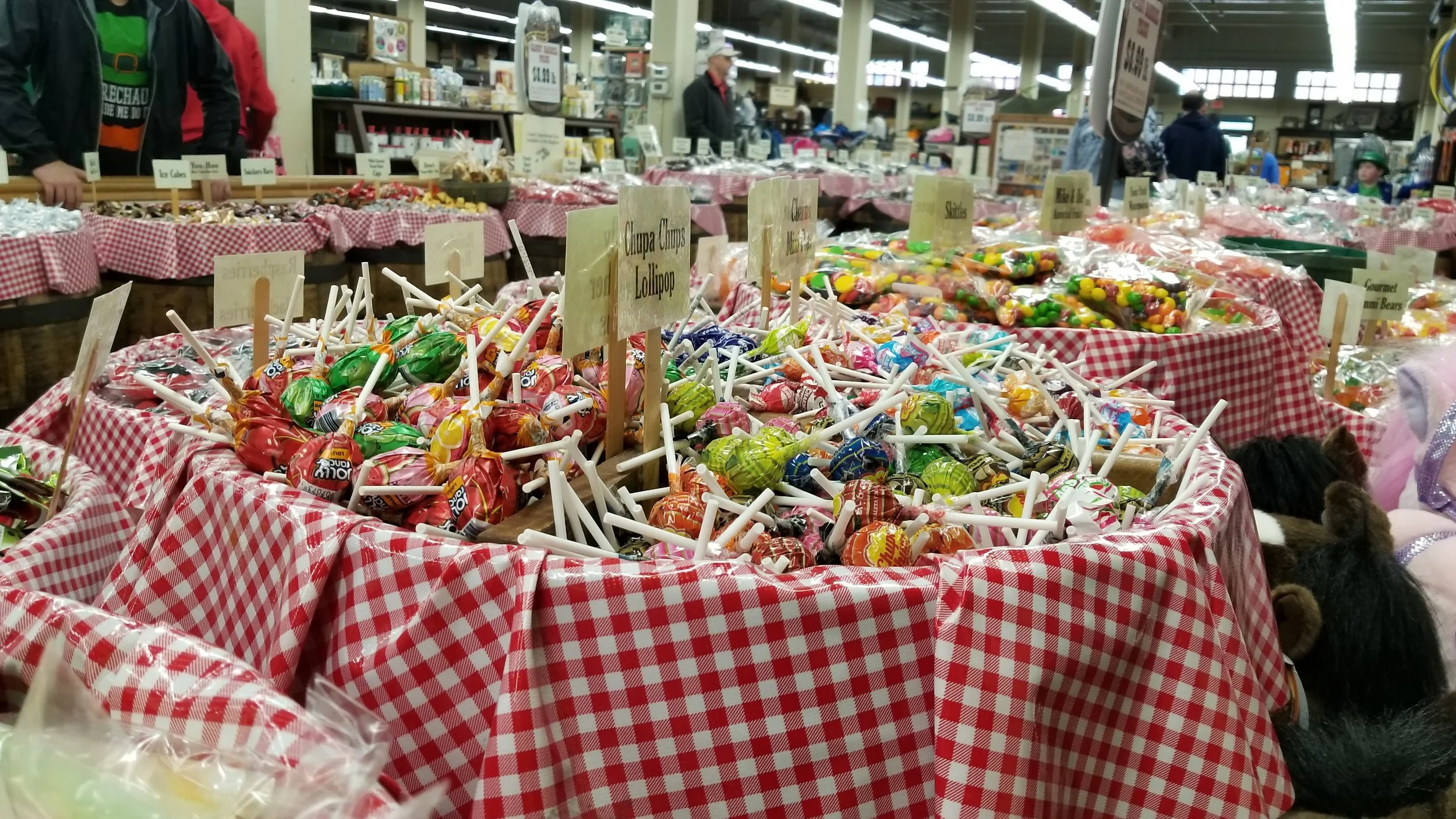 hundreds of lollipops fill a barrel lined with red and white checkerboard fabric