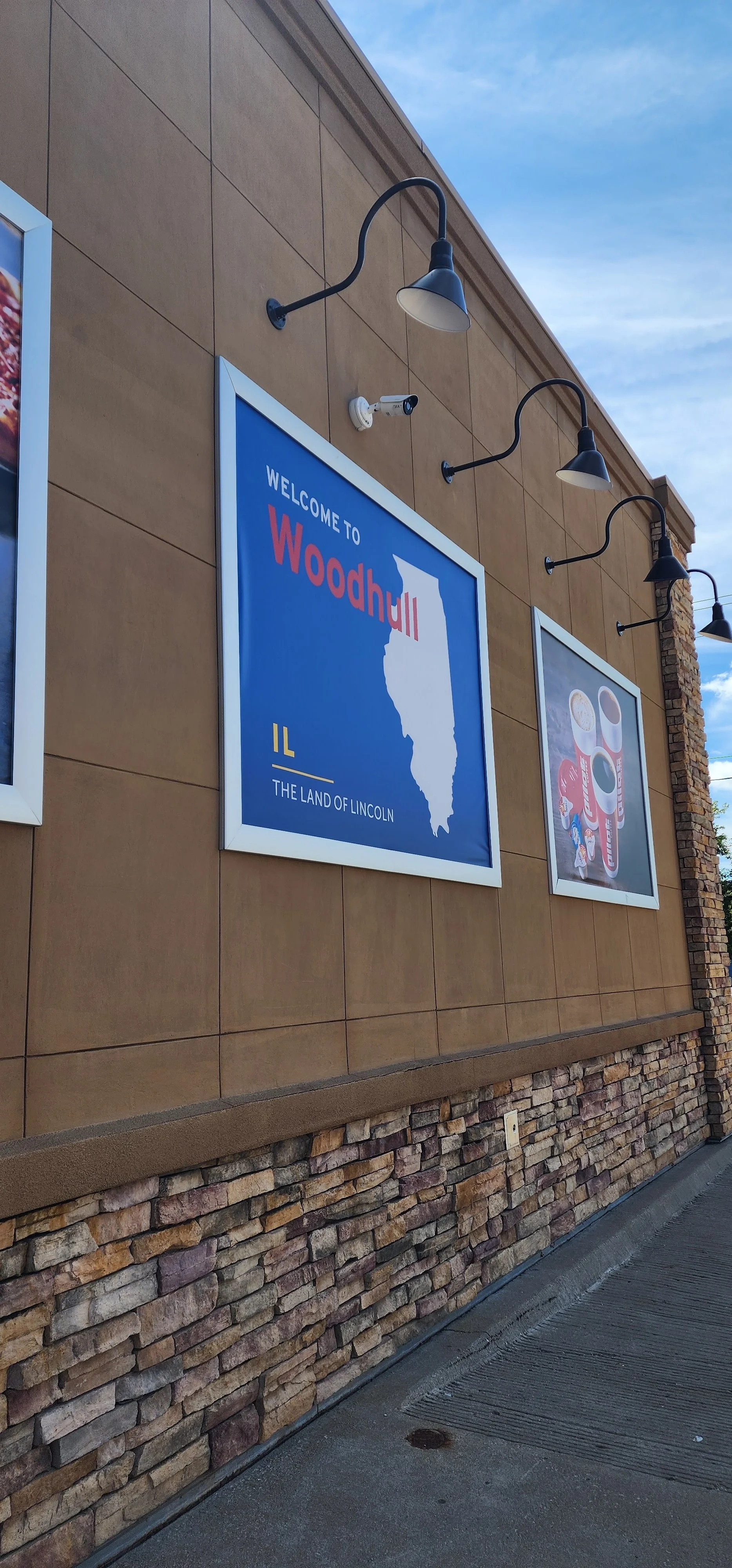 a sign saying welcome to woodhull illinois wiht another sign of pilot branded cups of beverages