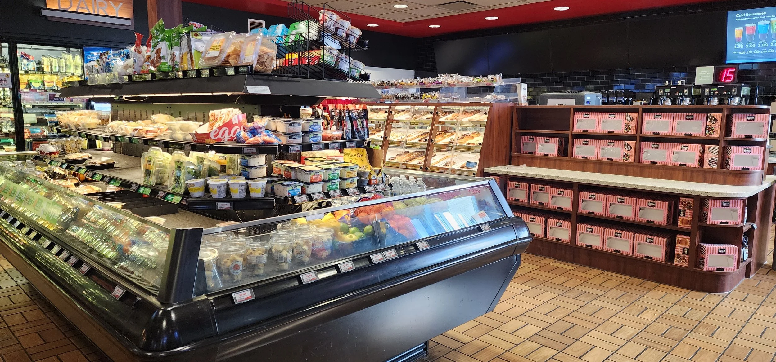 open coolers filled with fresh food items and racks of bakery items in the background