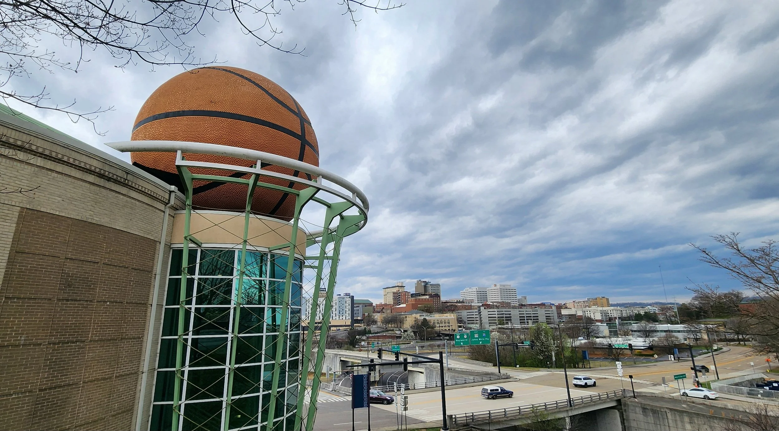 The world's largest basketball sits on top of a big hoop atop a museum dedicated to Women's basketball. In the distance is the skyline of Knoxville Tennessee