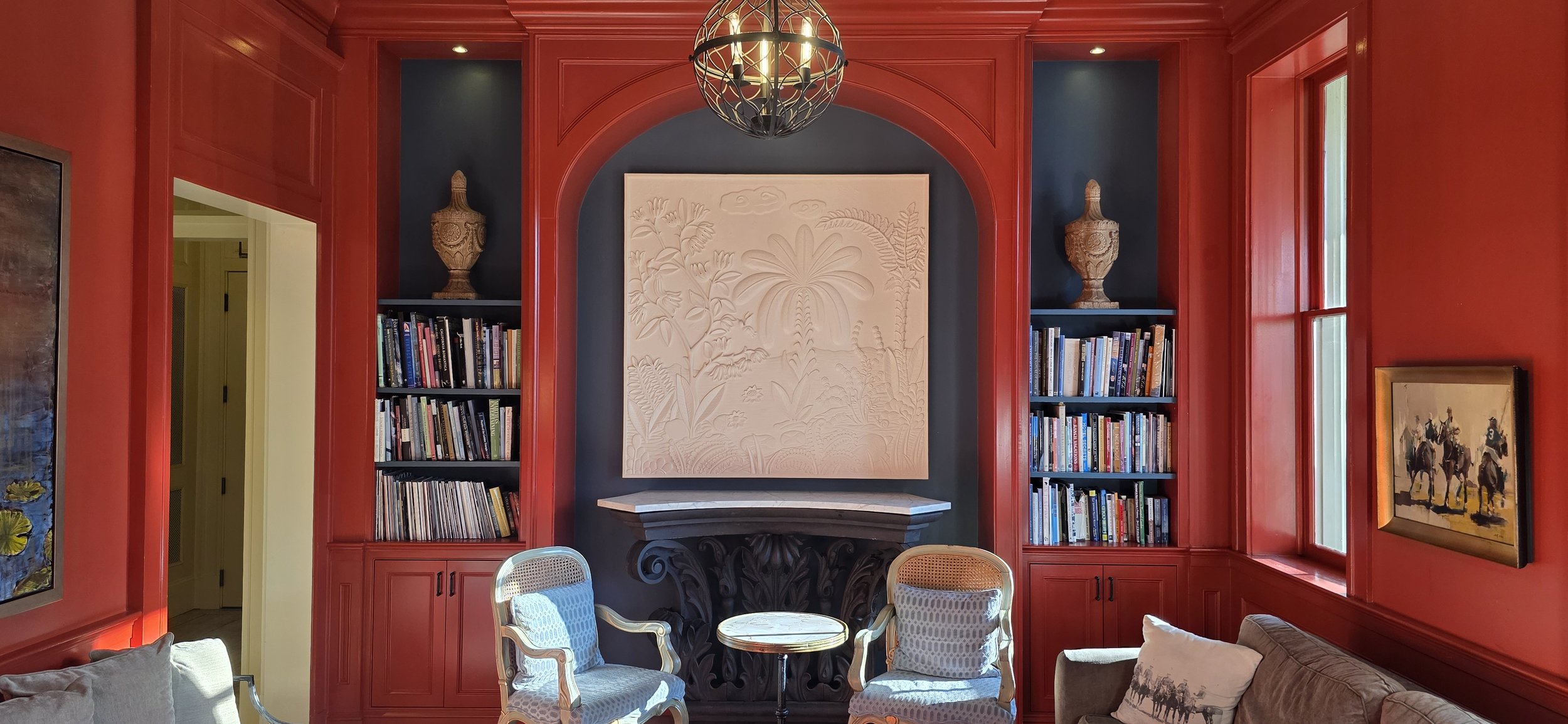 A bright red room with bookshelves and artwork inside the Southern Hotel