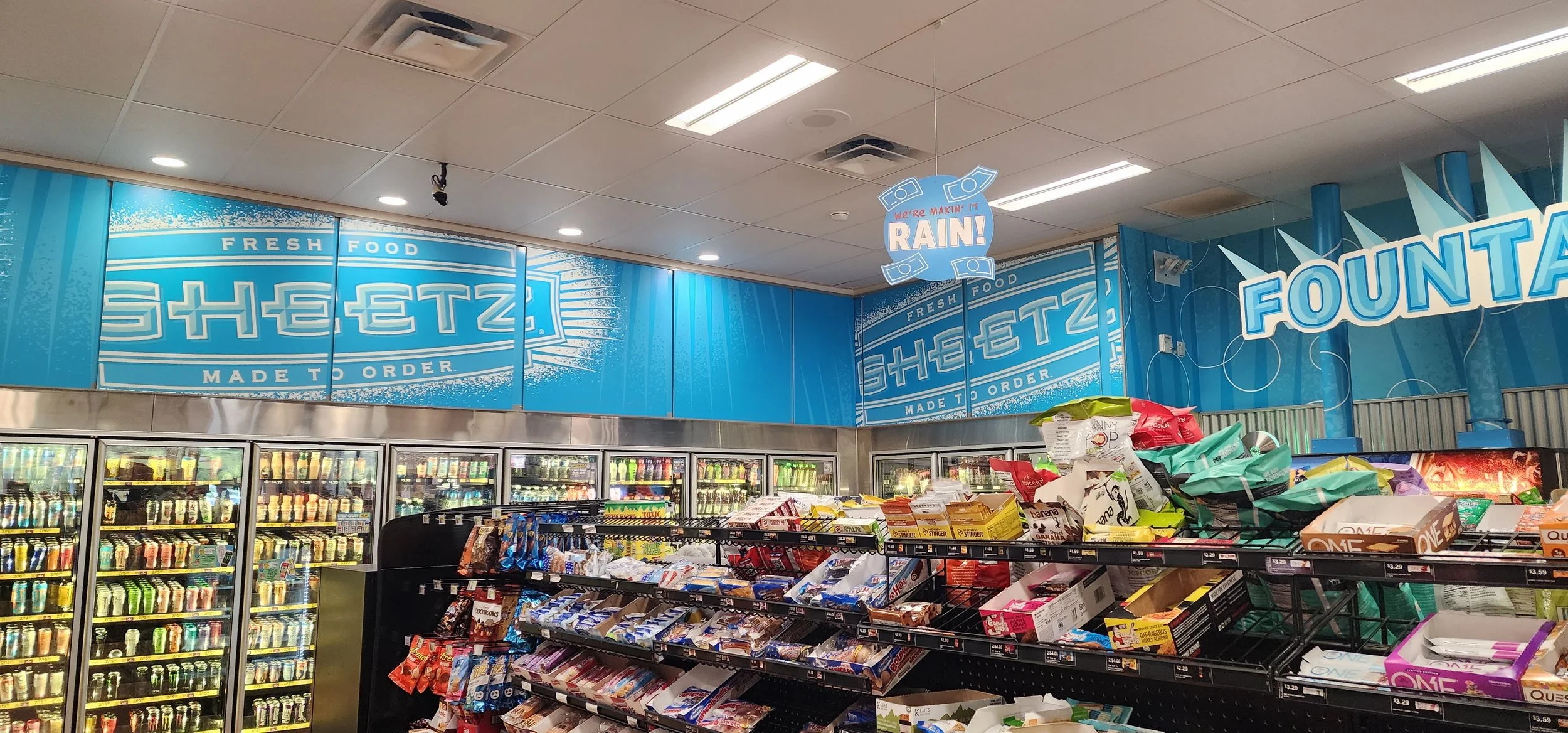 Light blue walls with the Sheetz logo are over a drink cooler.