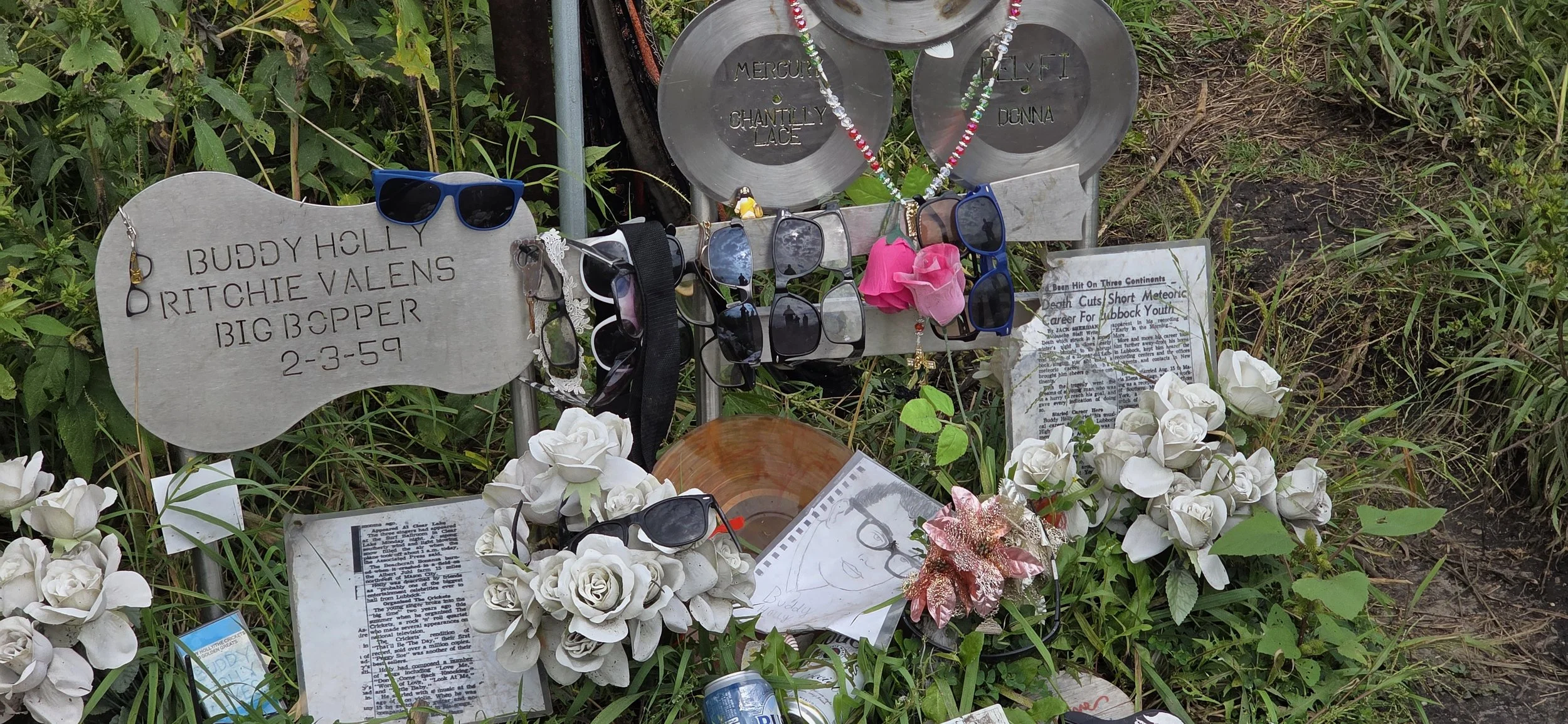 A steel shaped plate in the shape of a guitar bears the names of Buddy Holly, Ritchie Valens and Big Bopper