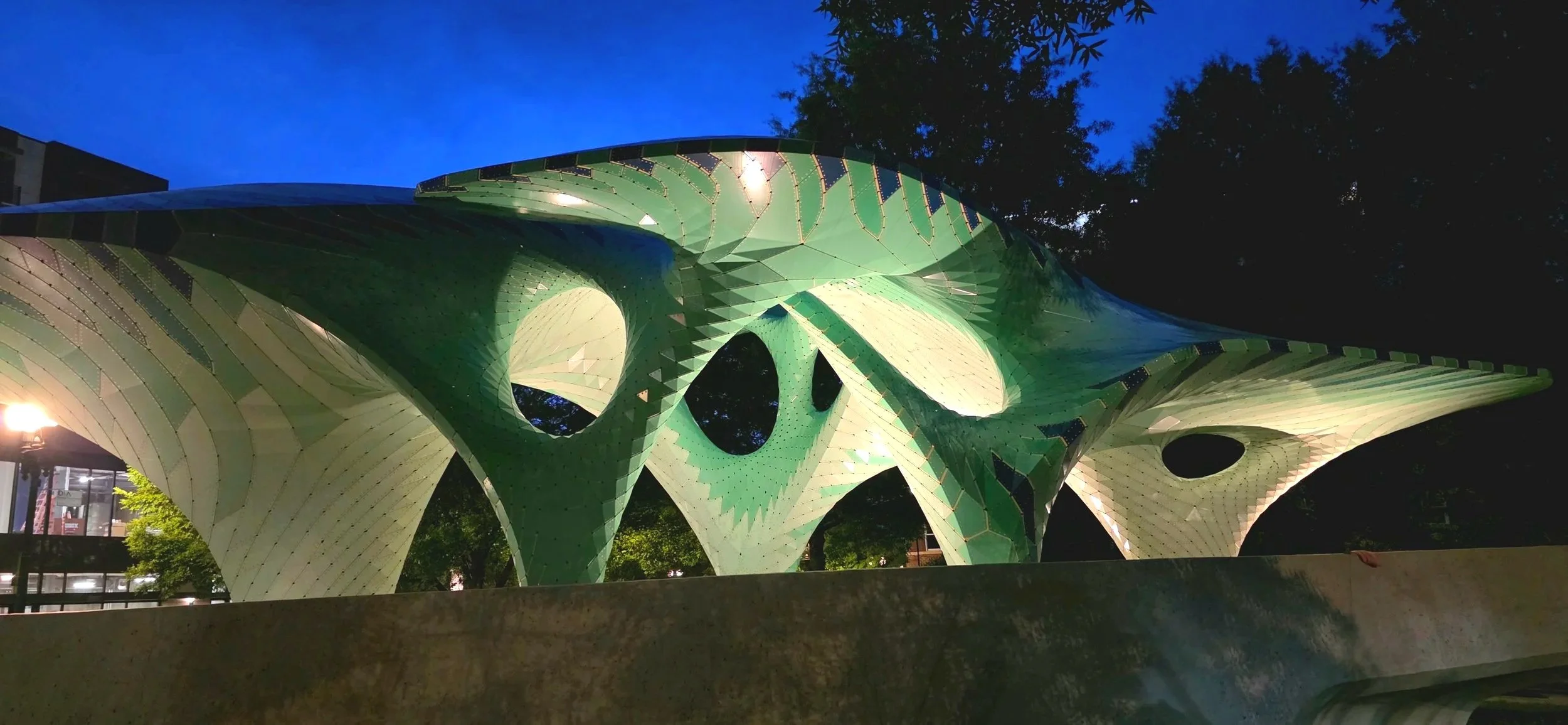 A large green sculpture with curved tops circular cutouts and flowing movement