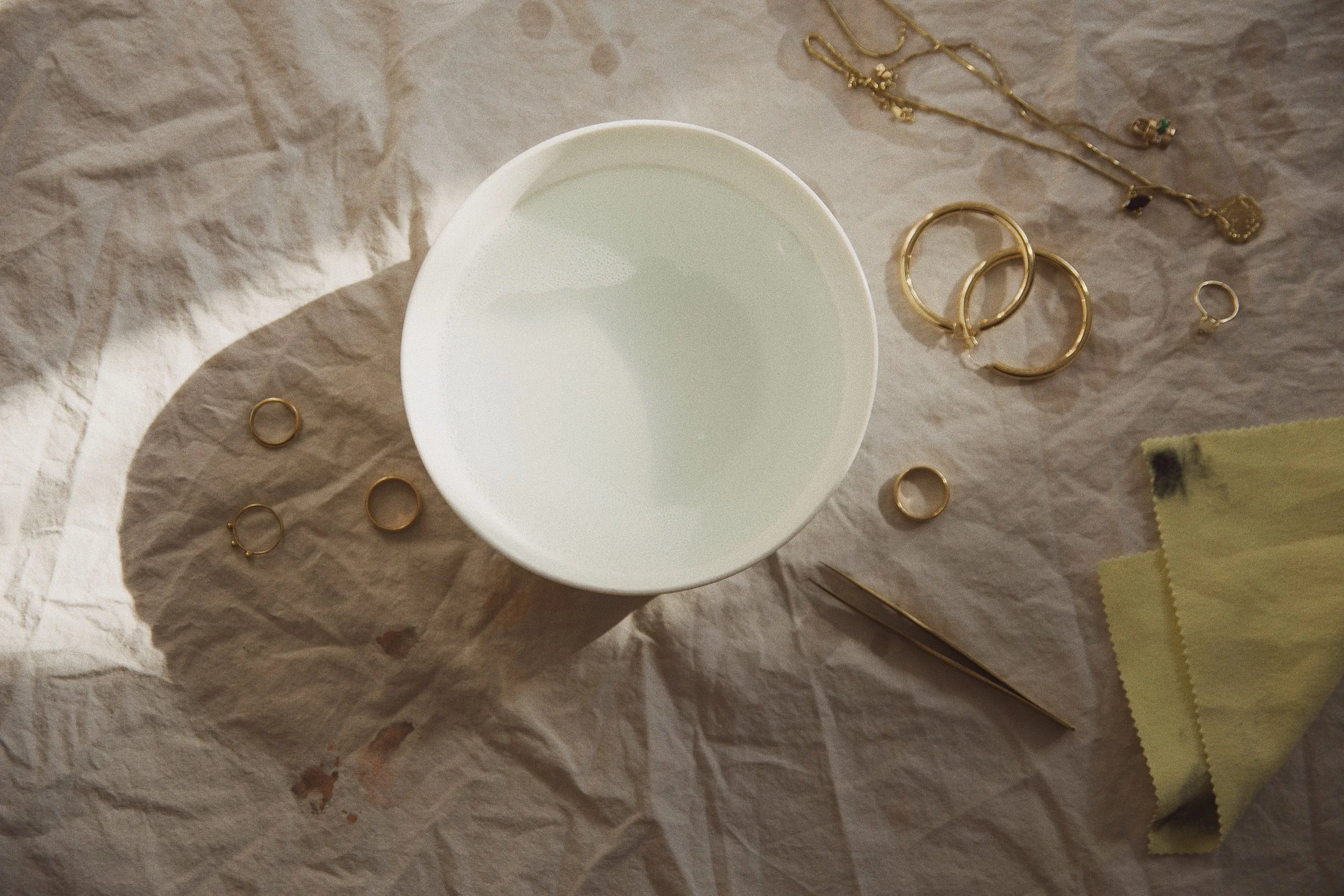 Create your own jewelry cleansing solution with mild soap and warm water. (I use dish soap at home) You can soak your jewelry overnight but do not soak soft gemstones such as emeralds or opals. For more durable pieces that are pure gold or diamonds, you may even soak your jewelry in soda water.