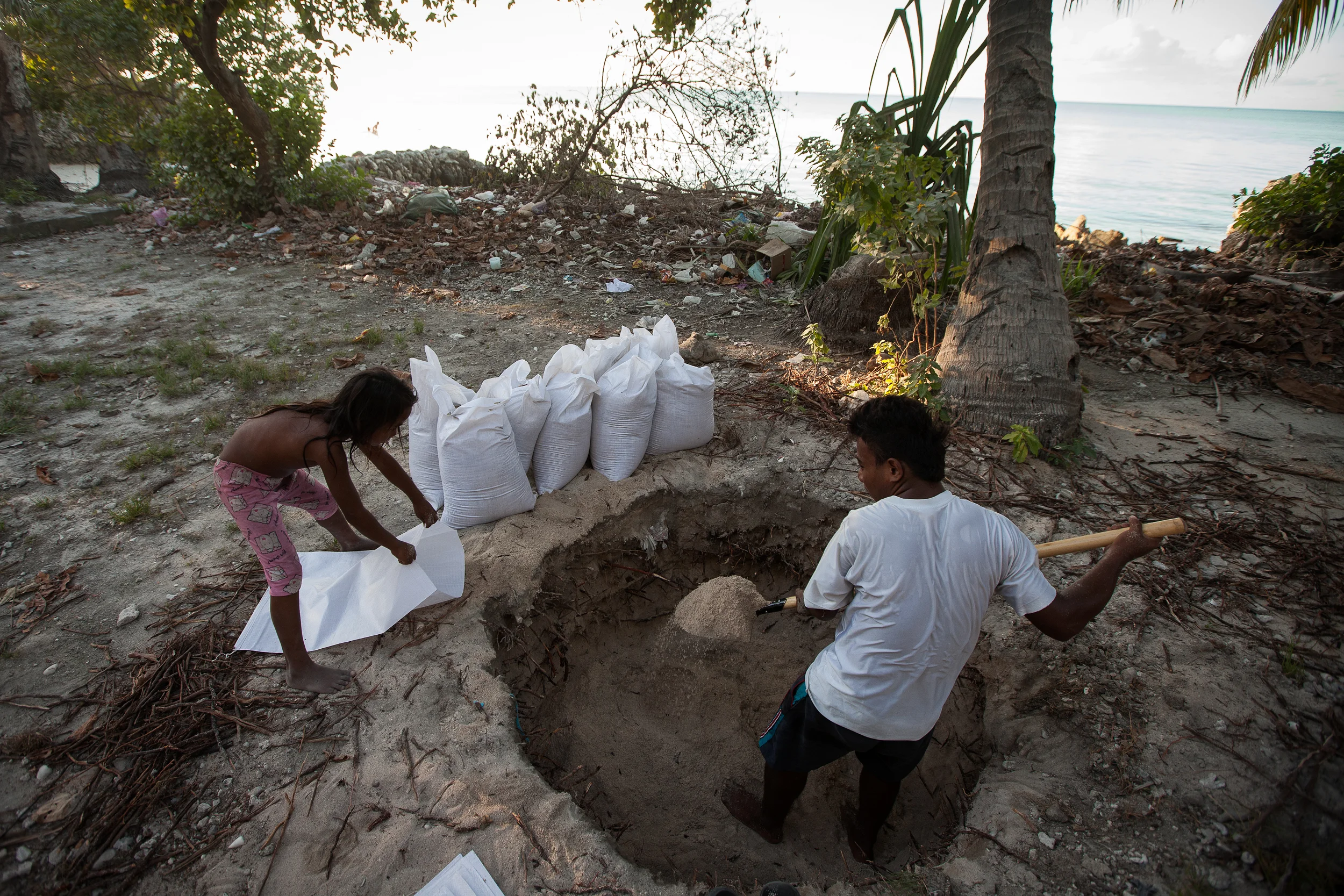 Iaonnatu Tikabenca, 26, and his cousin Aroua Kuratake, 8, fill bags with sand from the lagoon side of South Tarawa that will be used by their uncle to build a seawall on the ocean side of the atoll.