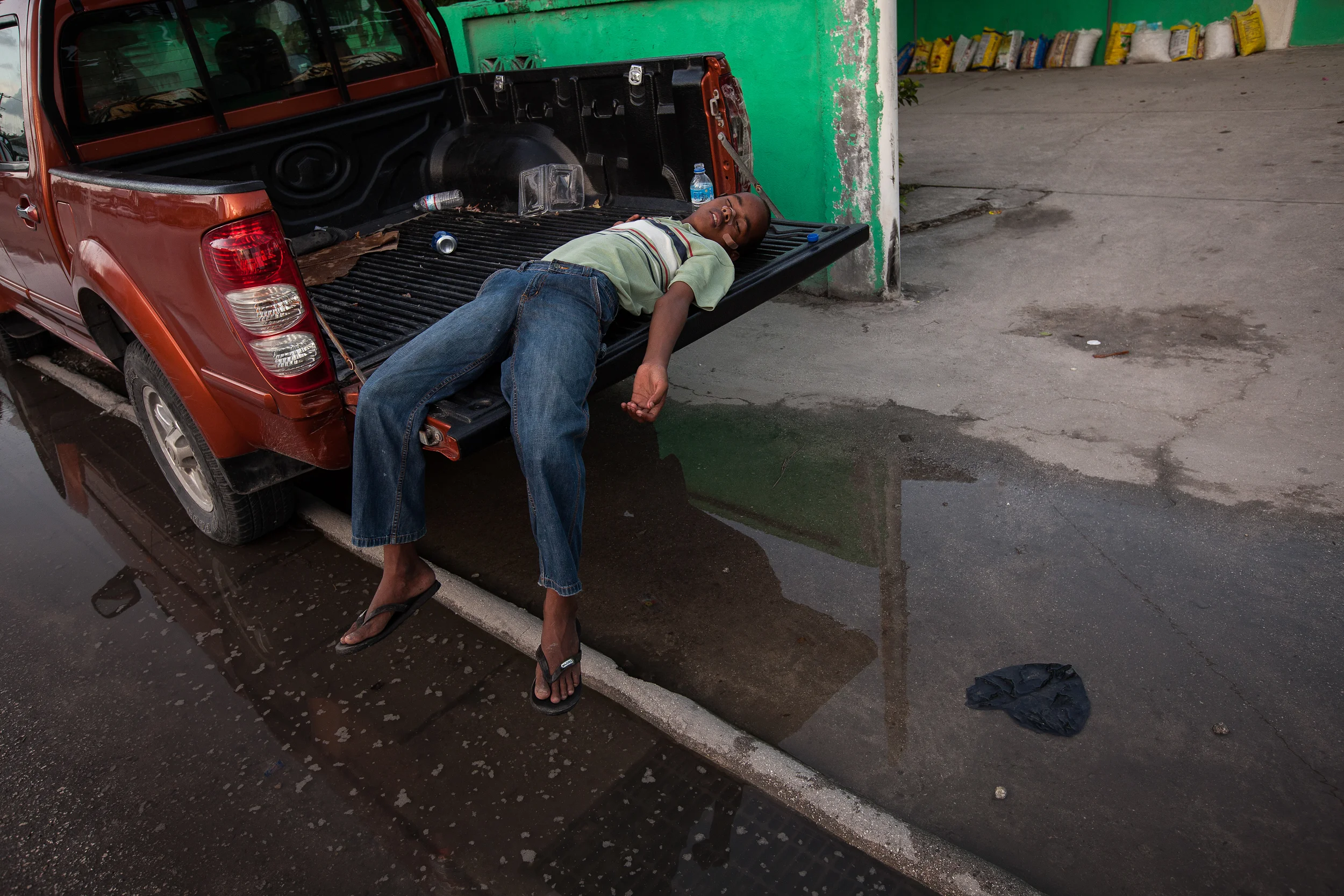 Tired from loading sandbags, a young man takes a nap between rain fronts. Some Marshallese houses have sandbags ready at both the front and back doors, to use depending on which side the water will come in from.