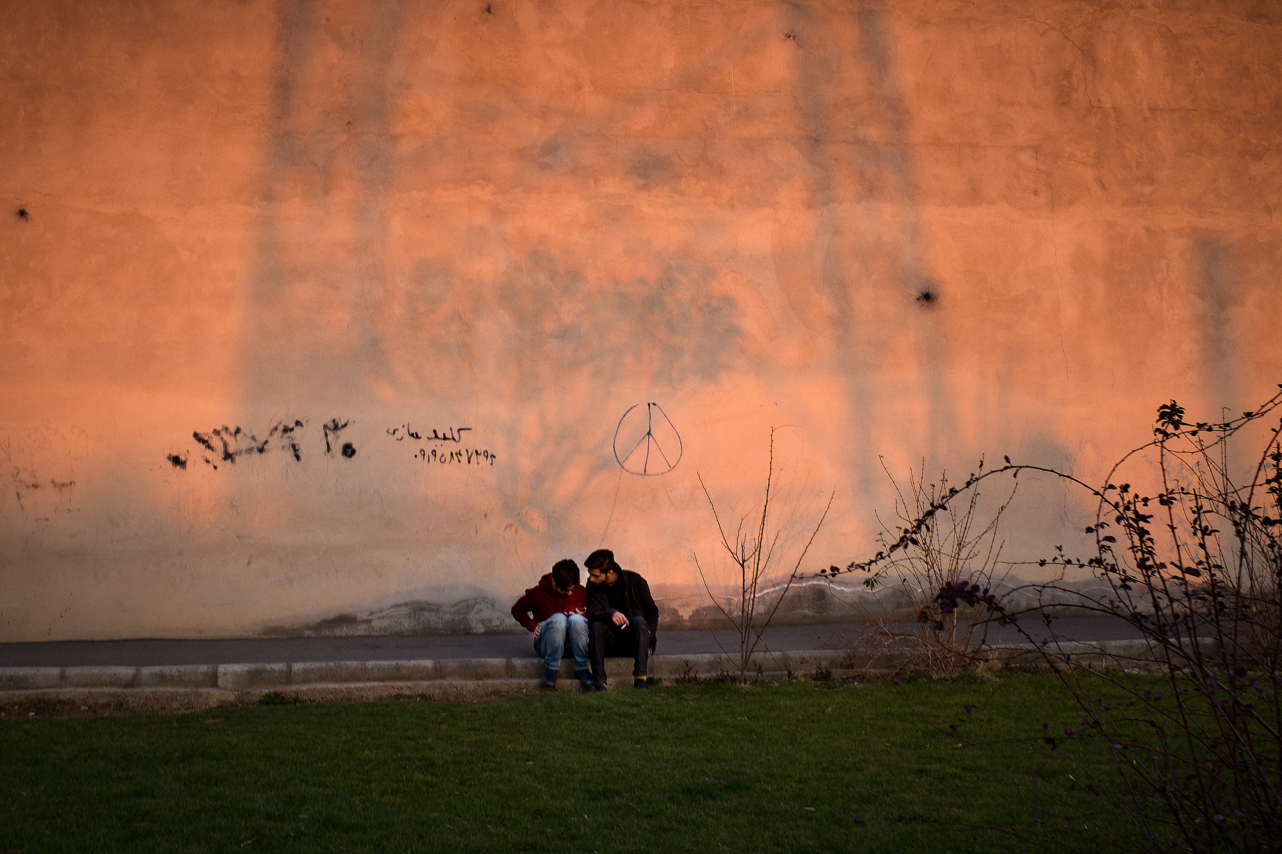 Two young men check their Facebook under graffiti in Western Tehran. Facebook is banned in Iran, but most young people freely access the site through the use of proxy defying software like Tor.