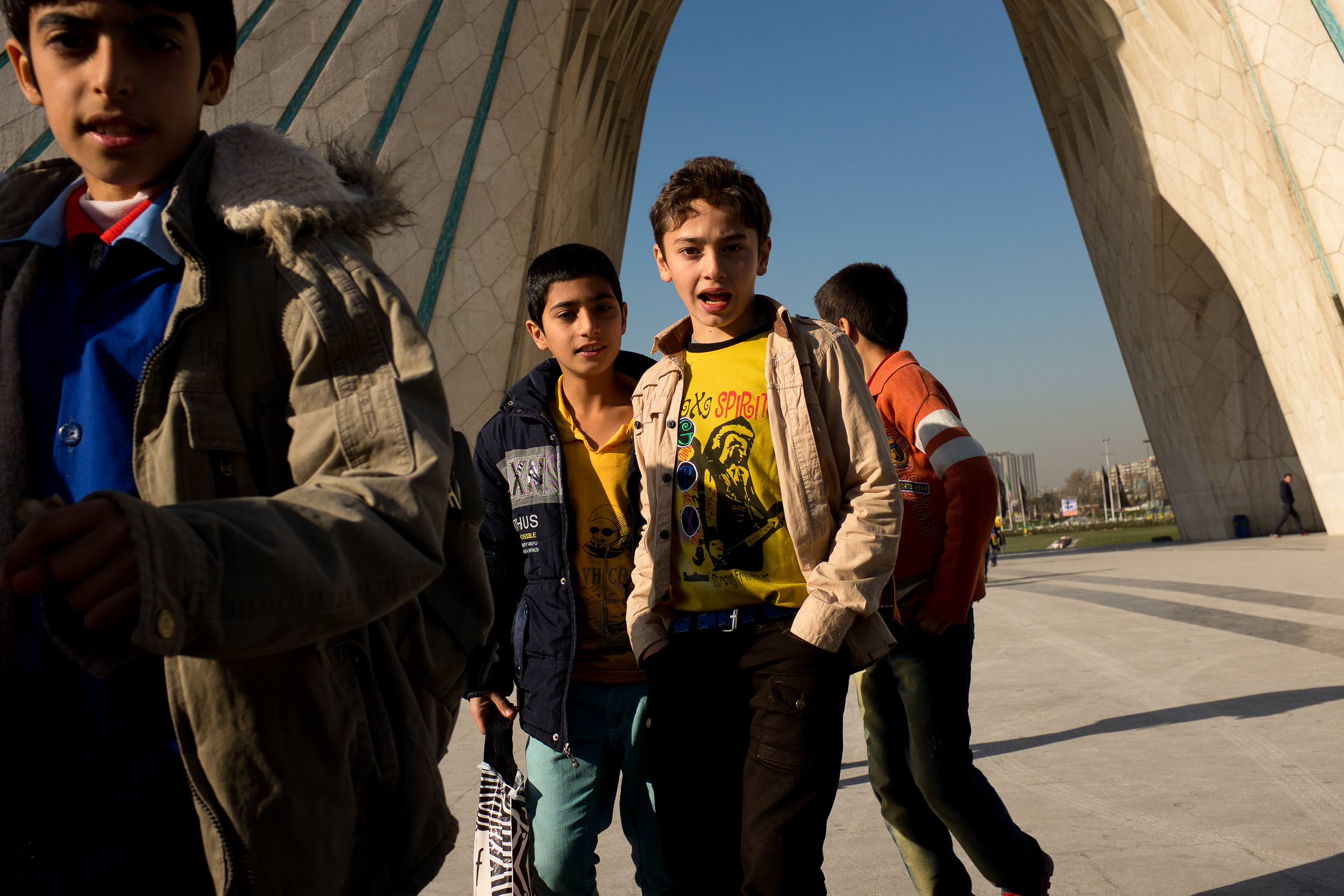 Children on an excursion run underneath the Azadi Tower in Tehran.