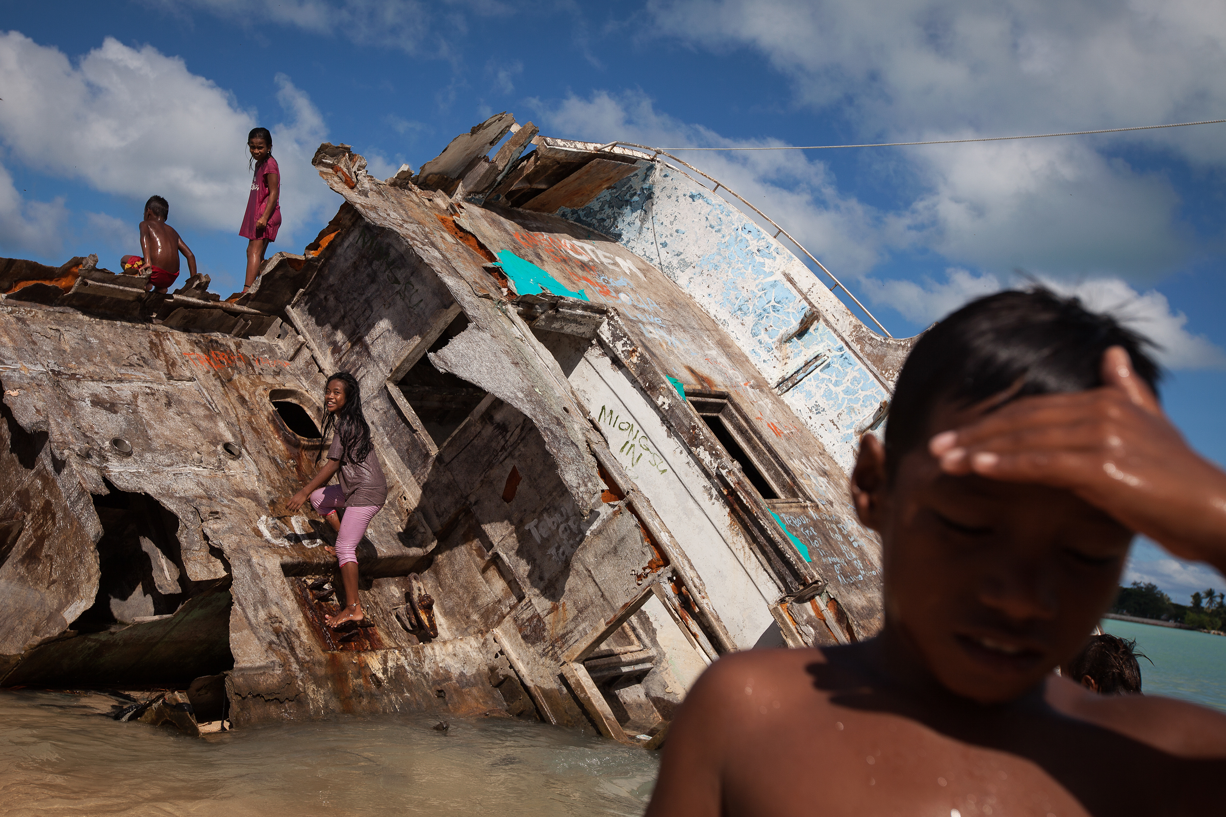 A boat washed ashore on Red Beach during a storm in 2013 now serves as play equipment for the local Betio kids. Betio is the most crowded and densely populated slum area in South Tarawa, with serious pollution and fresh water problems.