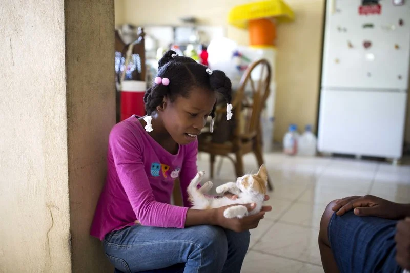 Franchina 11, plays with a cat at her foster home in Port-au-Prince, Haiti. (AP Photo/Dieu Nalio Chery)