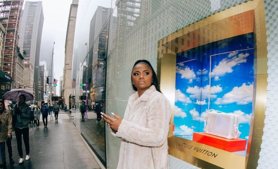 LaShonda Moore stands outside a Louis Vuitton store window display on a New York City street