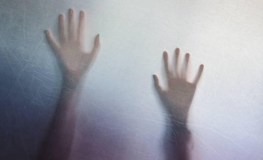 Two hands pressed against frosted glass, casting faint shadows through the translucent surface.