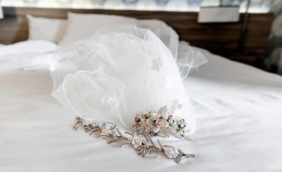 A bridal veil and jeweled hair accessories laid on white bedding