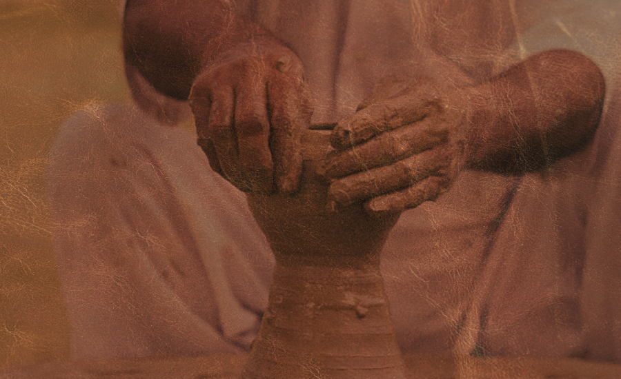 Sepia-toned image of a potter's hands shaping wet clay on a spinning wheel