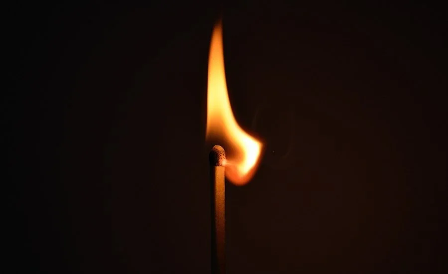 A single lit match burning against a dark background, illustrating Ephesians 5:8 and the call to walk as children of light