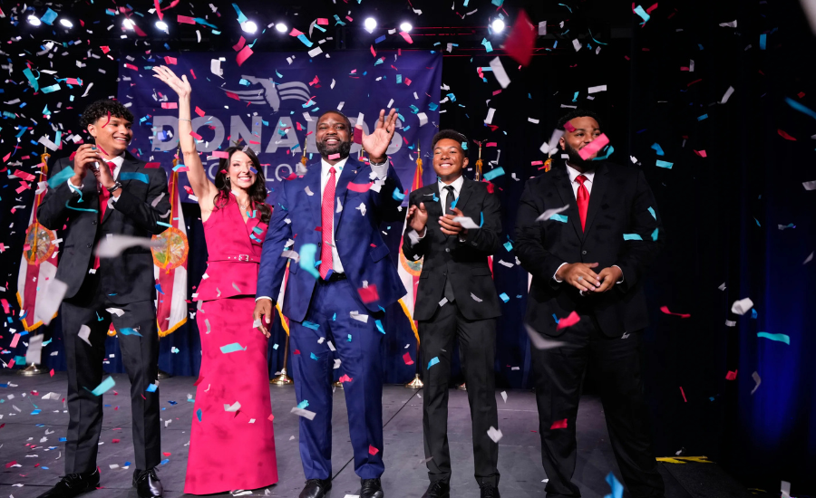 Byron Donalds and his family celebrate on a confetti-filled stage in front of a "Donalds for Florida" banner after his primary win.