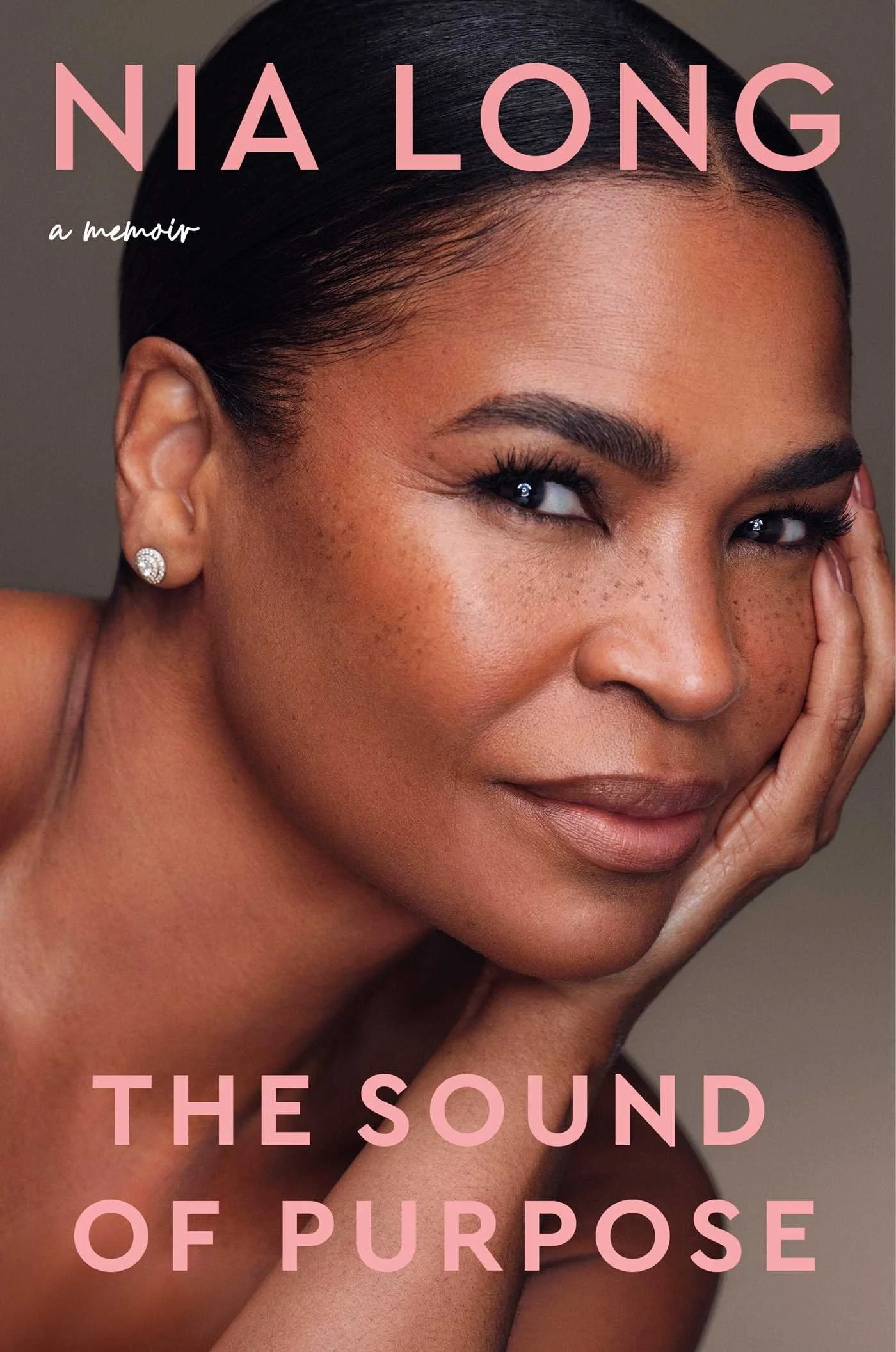Book cover of The Sound of Purpose: a memoir by Nia Long, showing a close-up portrait of Long resting her cheek on her hand against a warm taupe background, with the title and her name in pink capital letters.