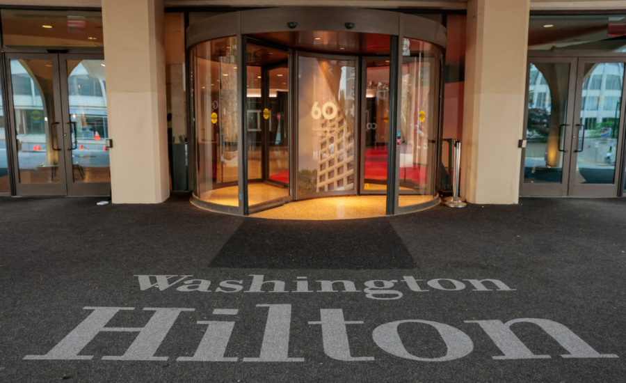 The revolving-door entrance of the Washington Hilton, with the hotel's name lettered across the carpet in the foreground.