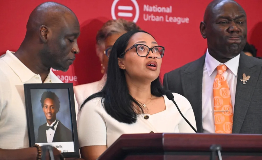 Christine Wonsley speaks at a podium while Elmore Wonsley holds a framed photo of their late son, Nolan Wells, during the National Urban League’s annual conference in Nashville, Tennessee.