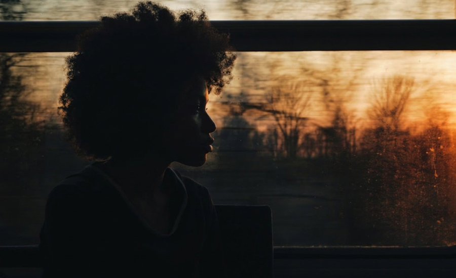 woman in silhouette gazing out a window at sunset, illustrating quiet endurance and faith that holds through unanswered prayer