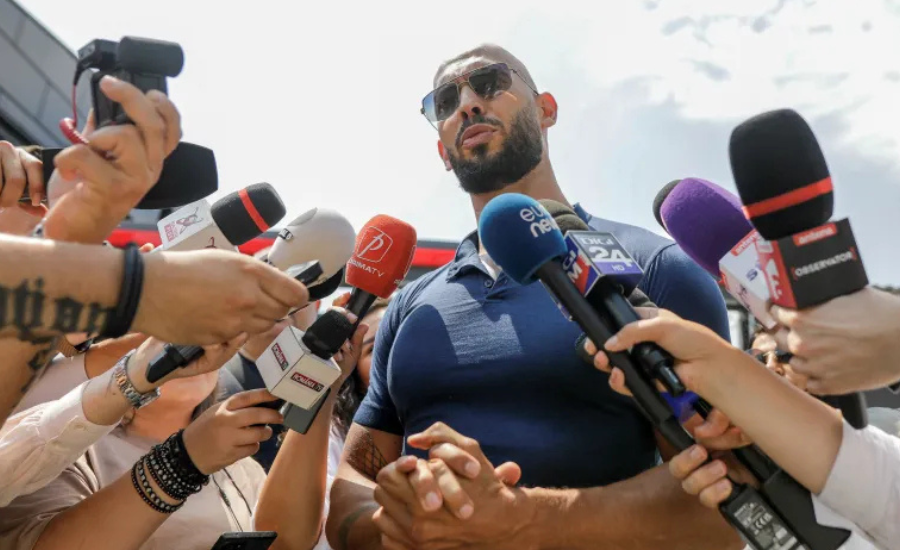 Andrew Tate speaks to a crowd of reporters and microphones outside his home in Voluntari, Romania