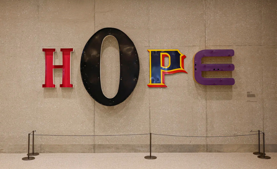A large-scale art installation of the word HOPE in mismatched colorful letters mounted on a stone wall inside the Obama Presidential Center museum tower